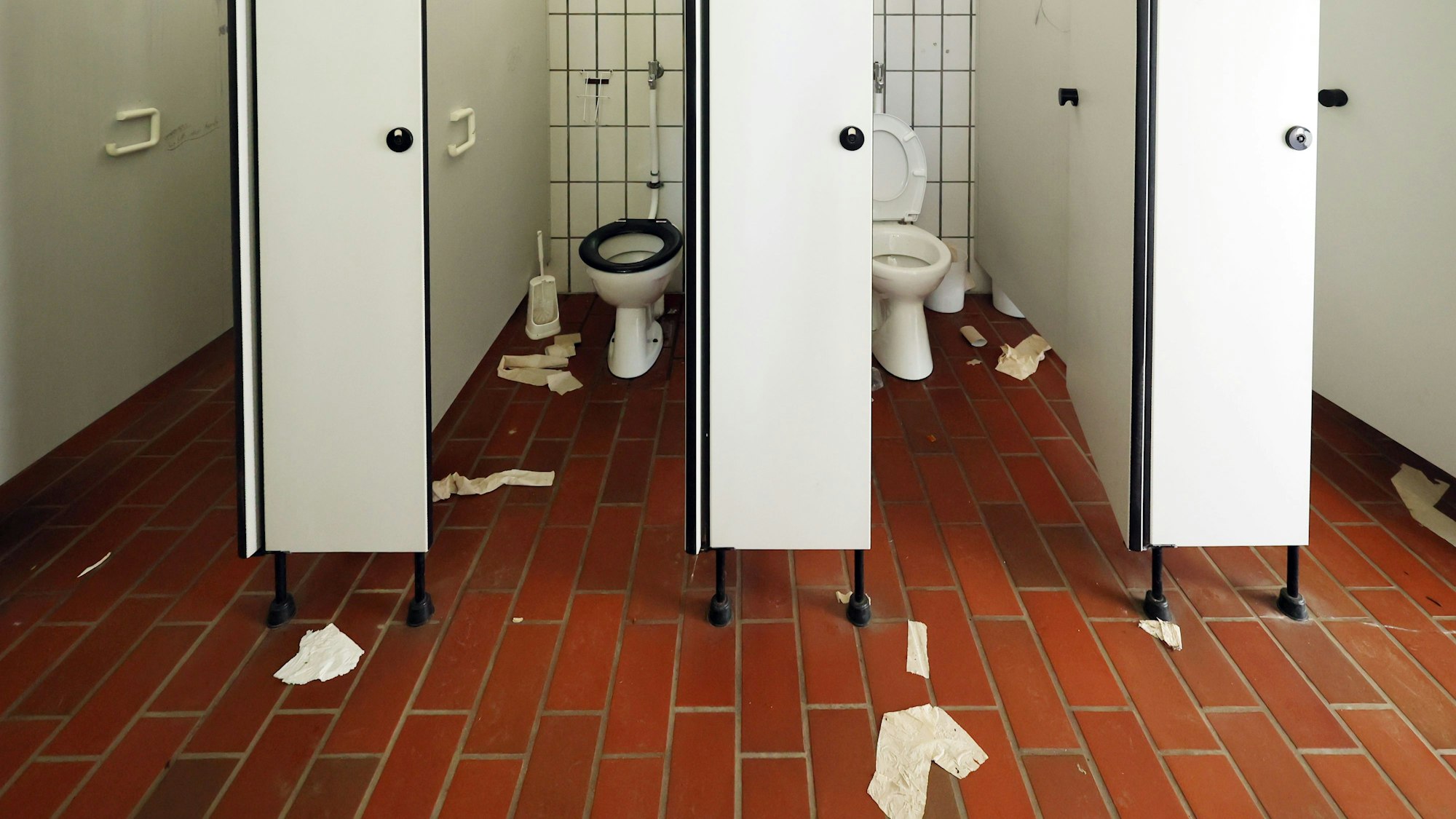 Auf dem Boden einer öffentlichen Toilette liegen Klorollen und Handtuchpapier.