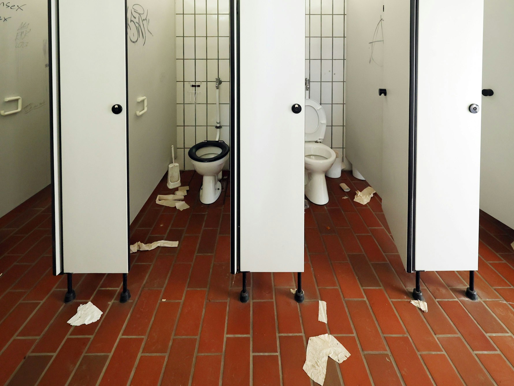 Auf dem Boden einer öffentlichen Toilette liegen Klorollen und Handtuchpapier.