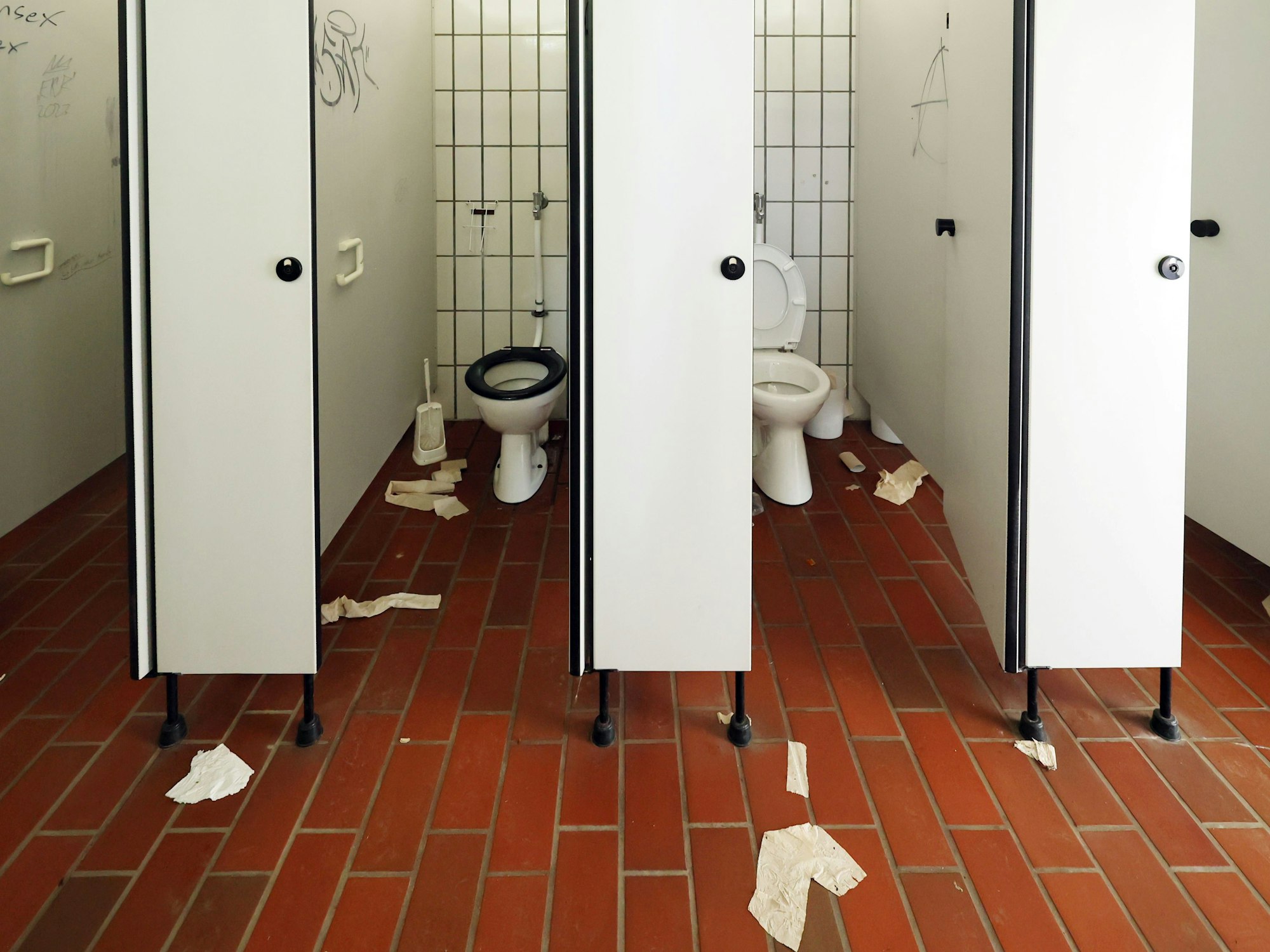 Auf dem Boden einer öffentlichen Toilette liegen Klorollen und Handtuchpapier.