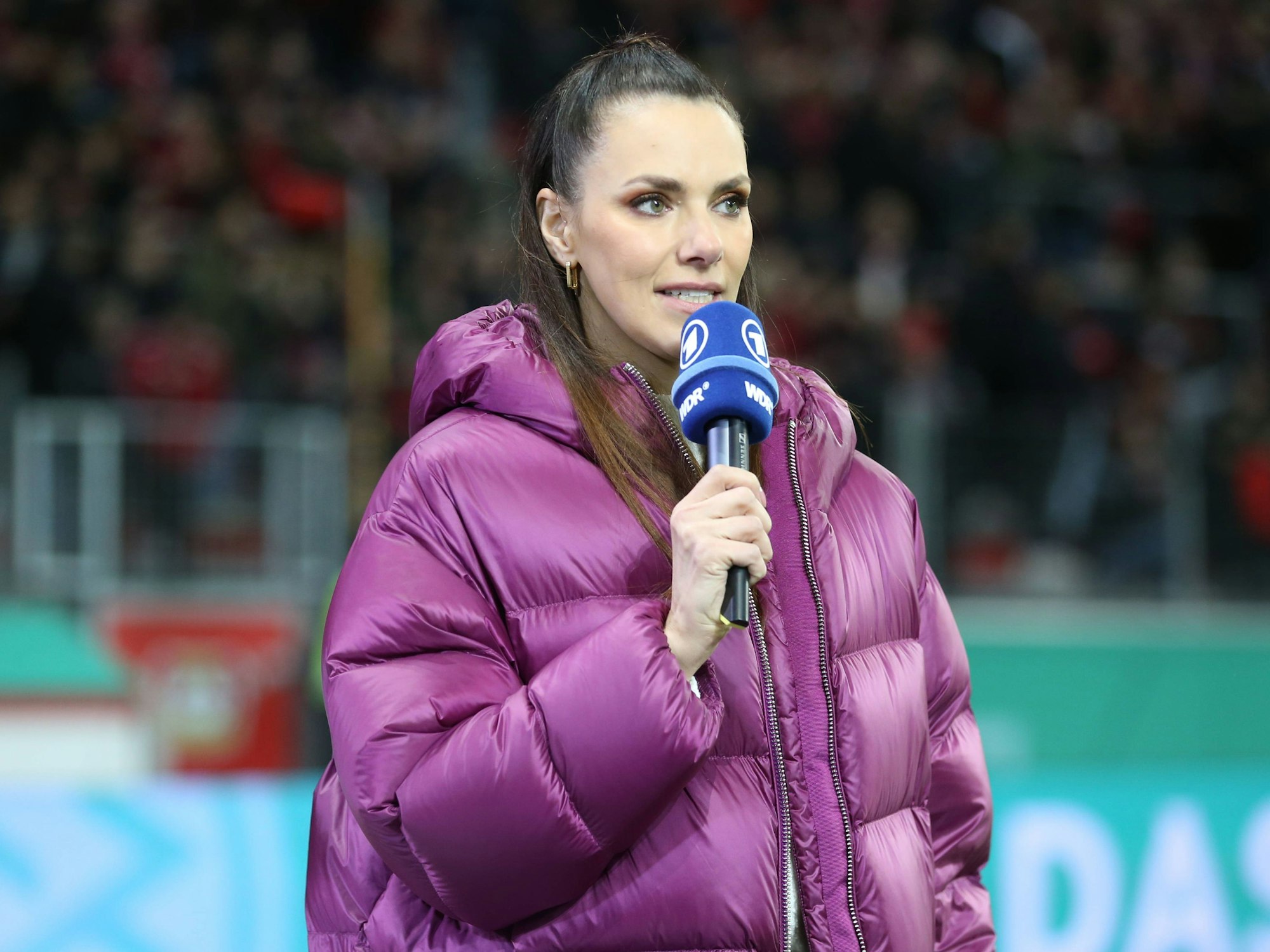 Moderatorin Esther Sedlaczek hält bei einer TV-Übertragung ein ARD-Mikrofon in der Hand.