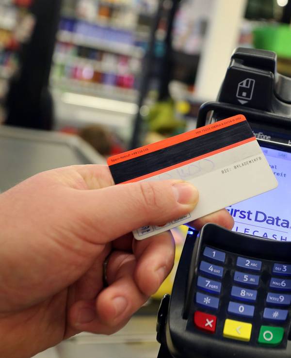 Eine EC-Karte wird an den Bezahl-Terminal an der Kasse eines Supermarktes gehalten.