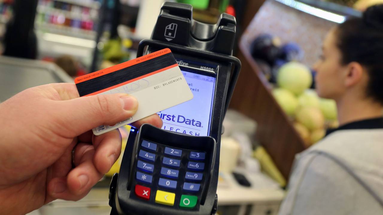 Eine EC-Karte wird an den Bezahl-Terminal an der Kasse eines Supermarktes gehalten.