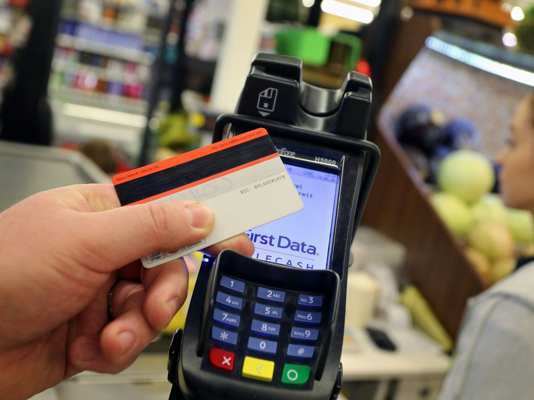 Eine EC-Karte wird an den Bezahl-Terminal an der Kasse eines Supermarktes gehalten.