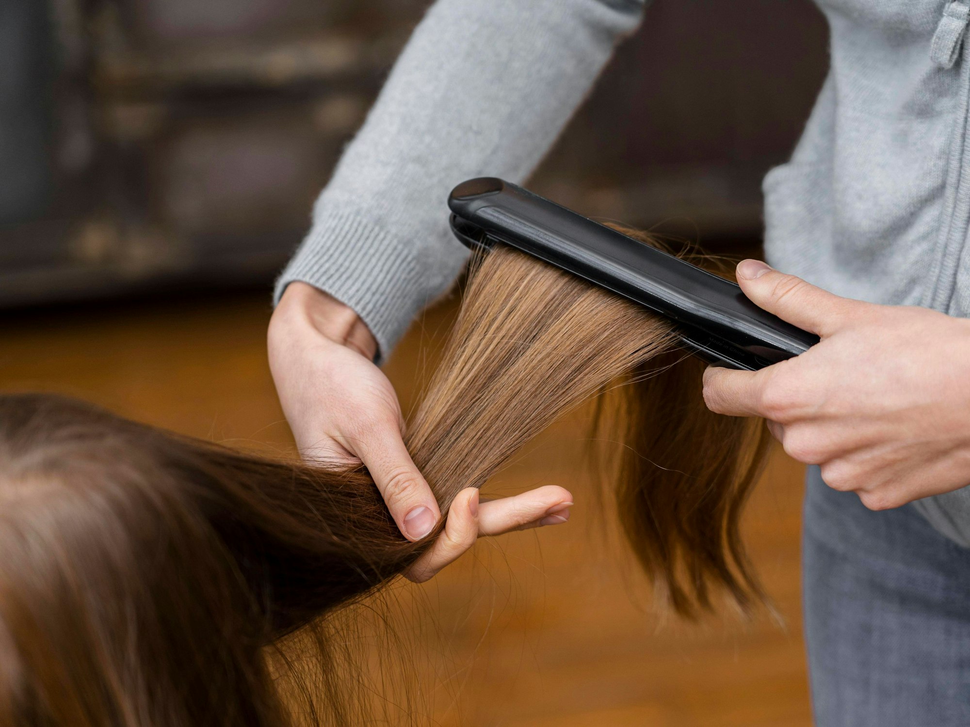 Ein Friseur glättet die Haare einer Kundin.