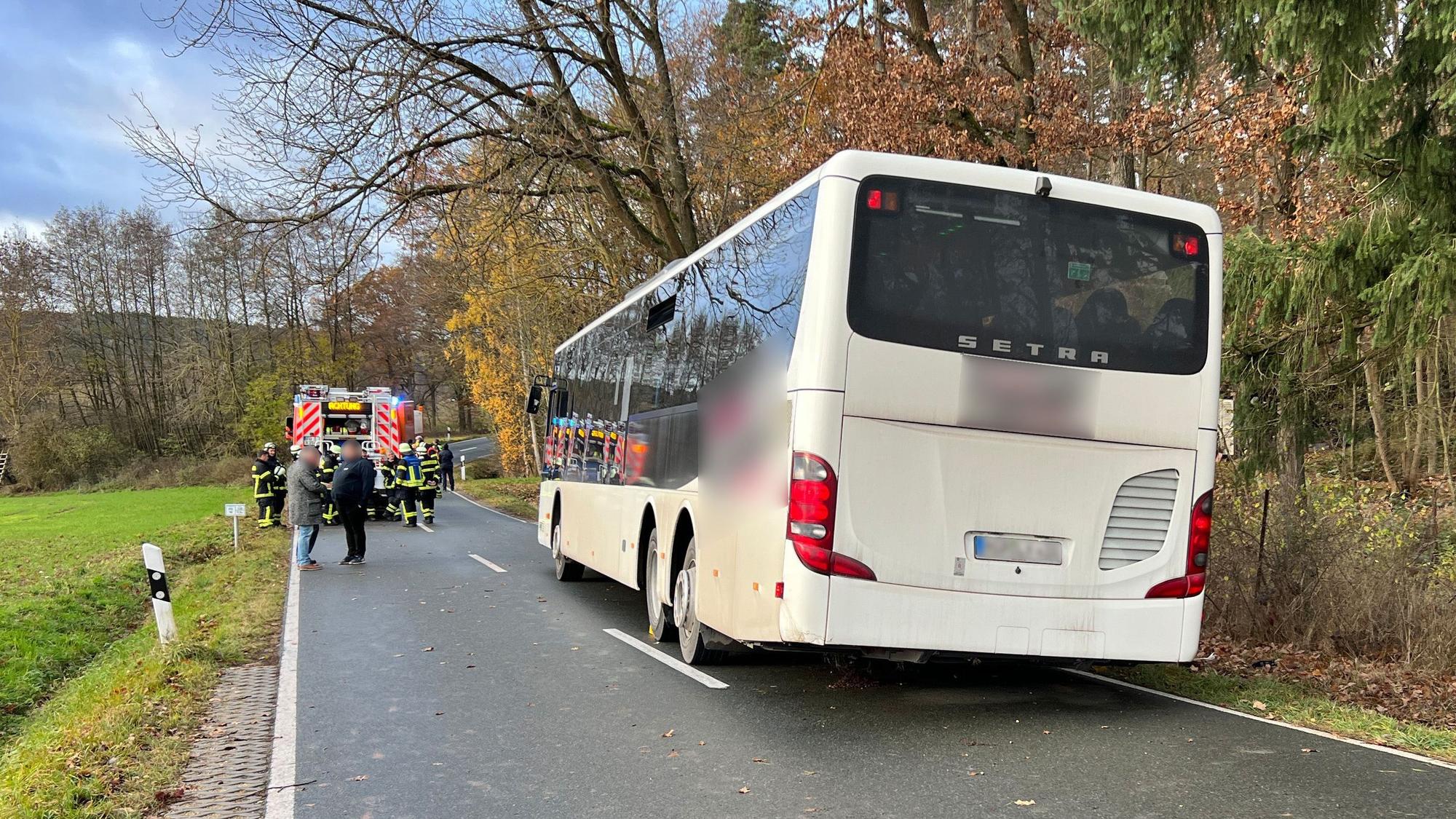 Bus steht auf einer Straße, im Hintergrund sind Einsatzkräfte der Feuerwehr zu sehen.