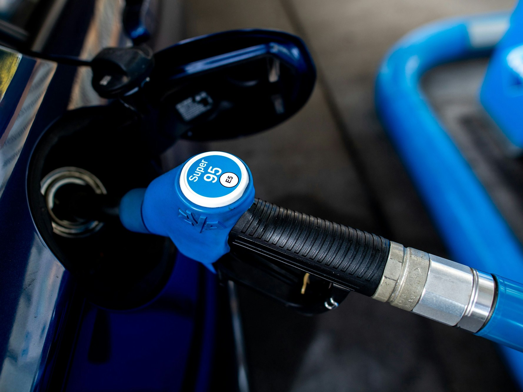 Eine Zapfpistole steckt in der Tanköffnung eines Fahrzeugs.