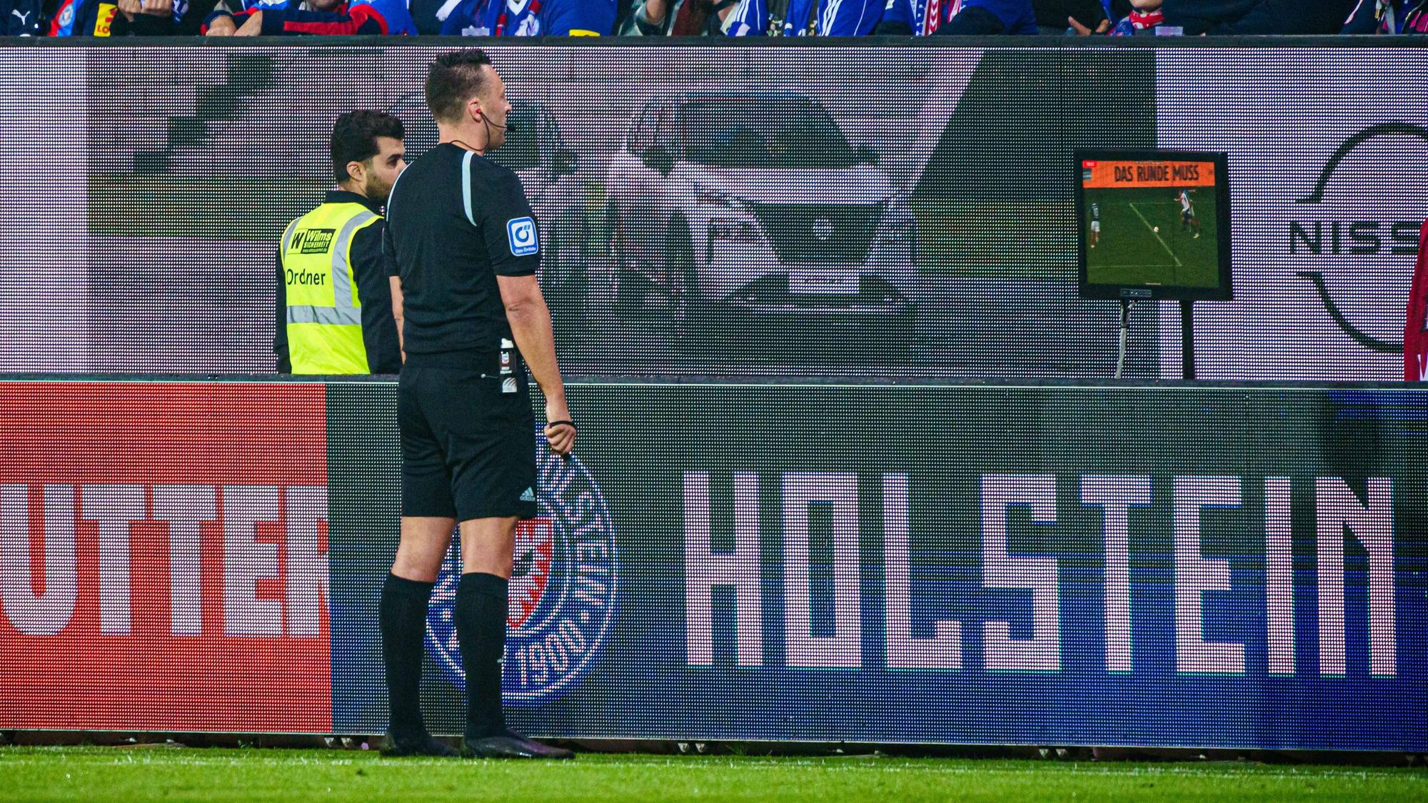 Schiedsrichter Sven Jablonski betrachtet beim Spiel Holstein Kiel gegen Fortuna Düsseldorf eine Szene am Video-Bildschirm.
