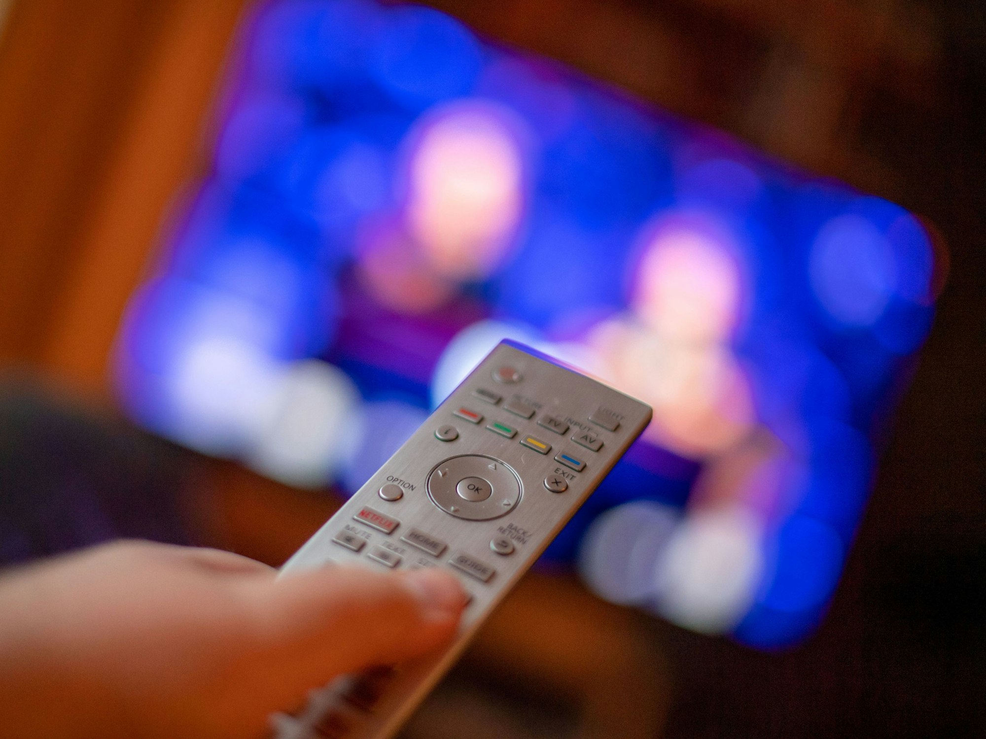 Ein Mann bedient mit der Fernbedienung einen Fernseher.