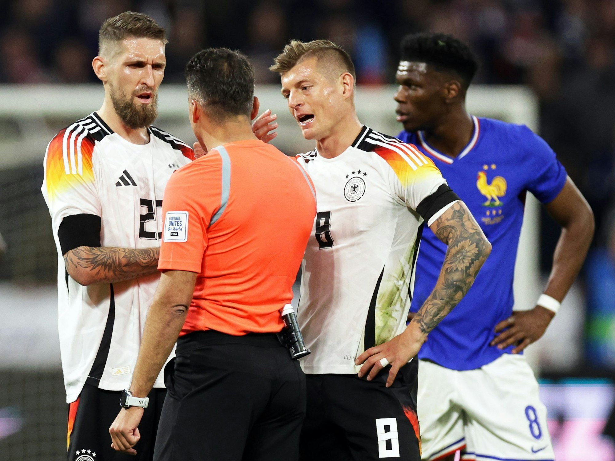 Deutschlands Spieler Robert Andrich (l) und Toni Kroos (2.v.r) diskutieren beim Spiel gegen Frankreich Mitte März mit dem Schiedsrichter.