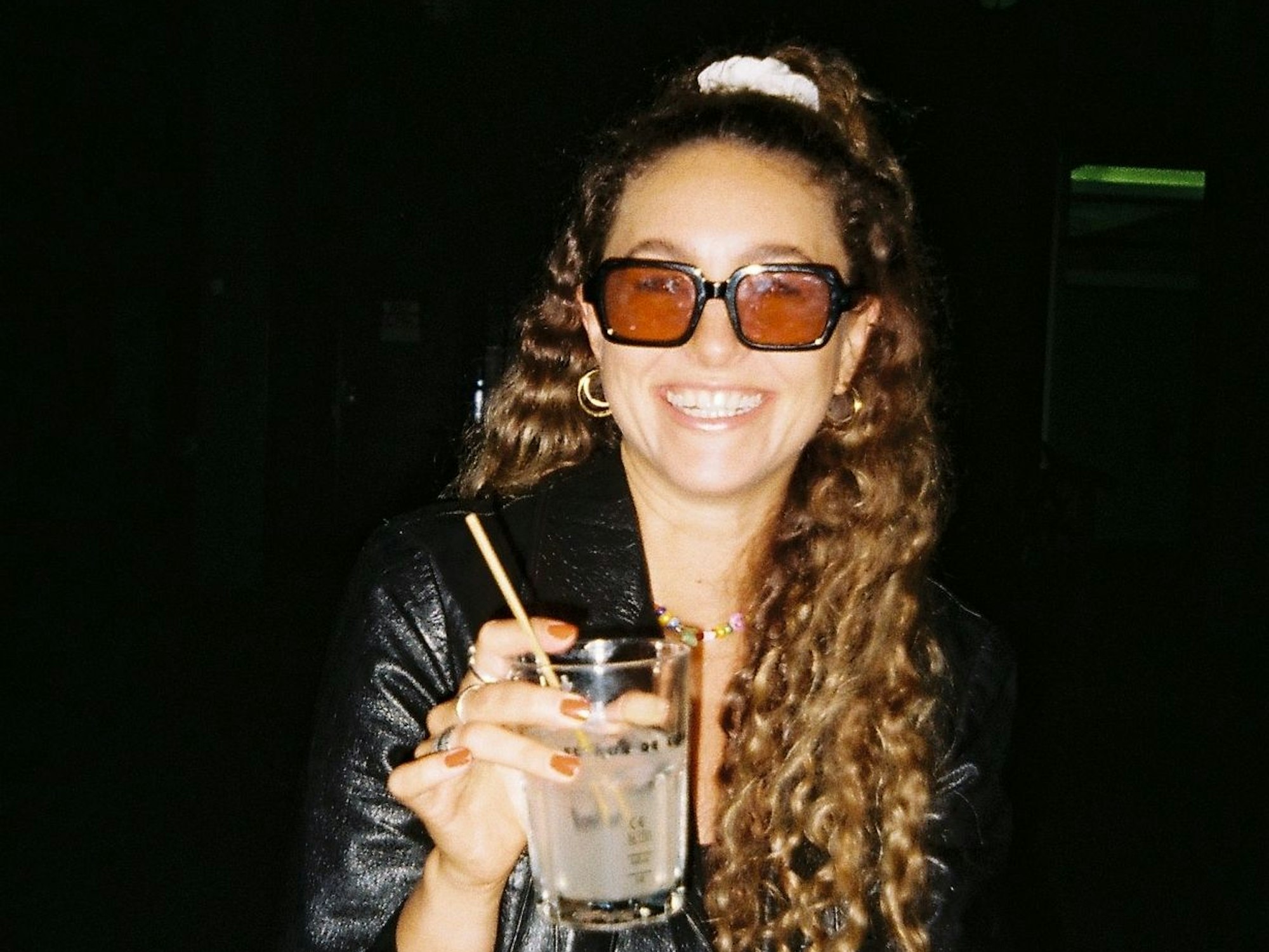 Kathi mit einem Drink in der Hand, sie lacht in die Kamera.