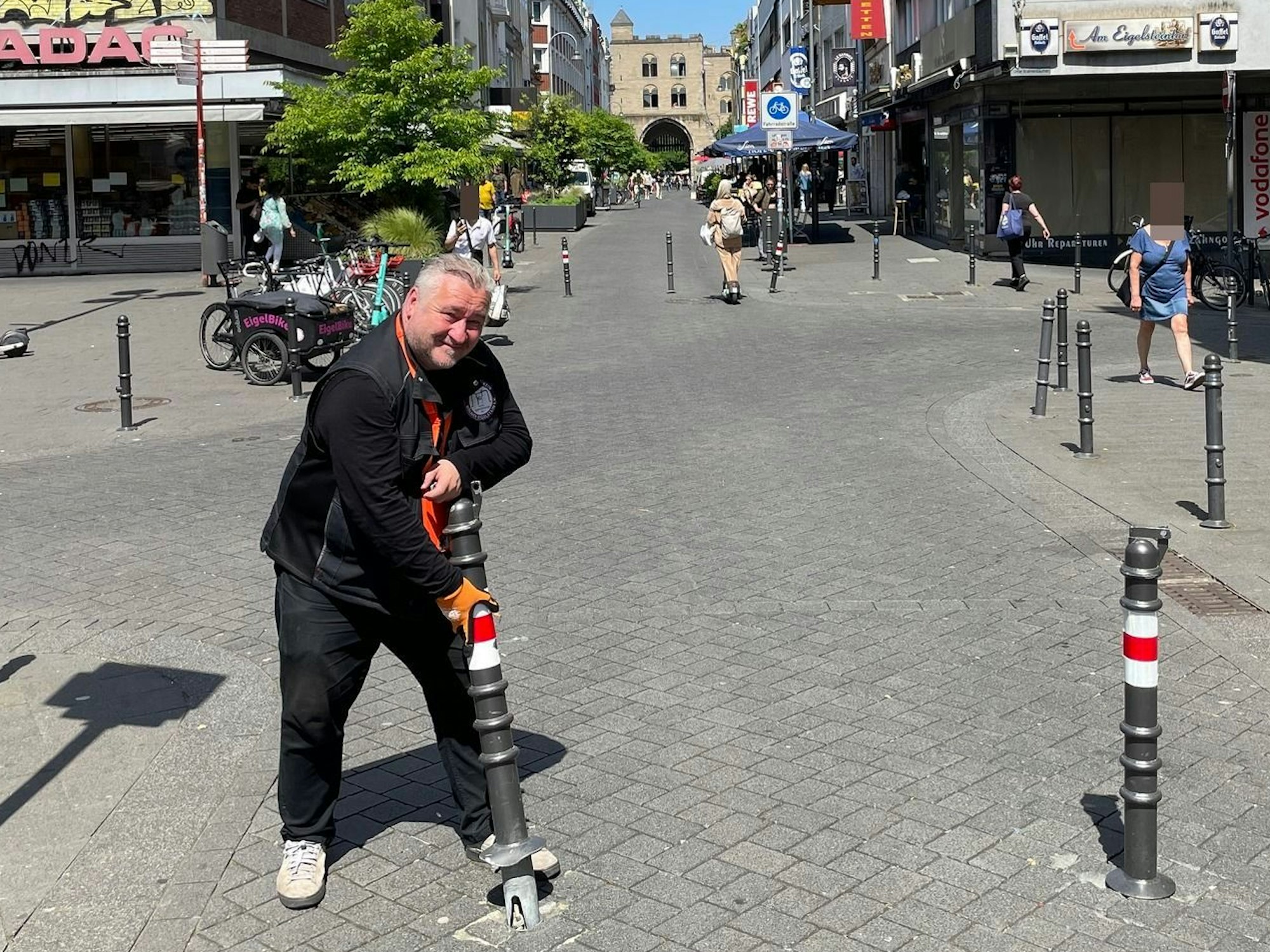 Ein Mann steht auf einer Straße und hat einen gelockerten Poller in Händen