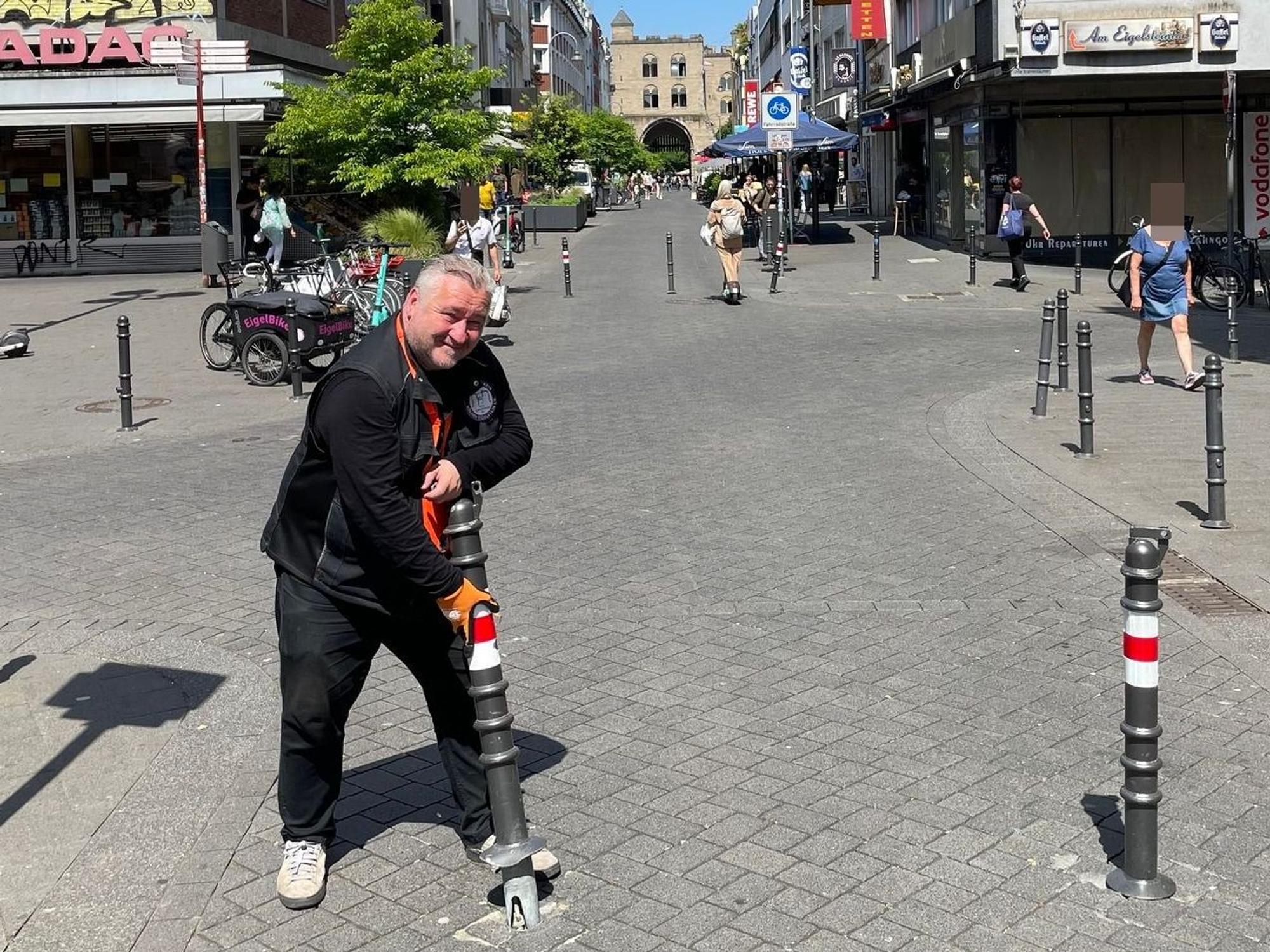 Ein Mann steht auf einer Straße und hat einen gelockerten Poller in Händen