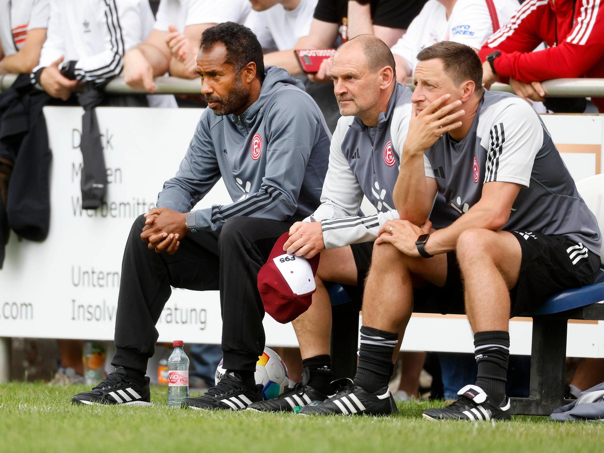 Fortuna Düsseldorfs Trainer Daniel Thioune beobachtet auf der Bank mit seinen Assistenten Manfred Stefes und Jan Hoepner sein Team im Testspiel gegen TuRu Düsseldorf.