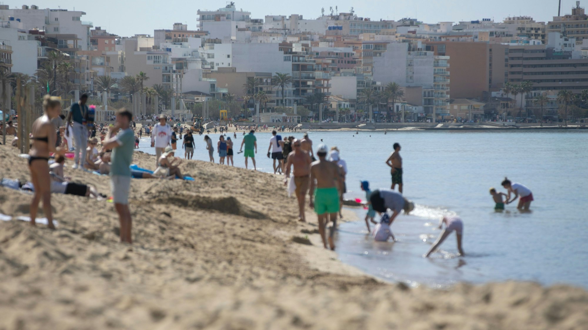 Menschen spazieren am Strand von Arenal auf Mallorca.