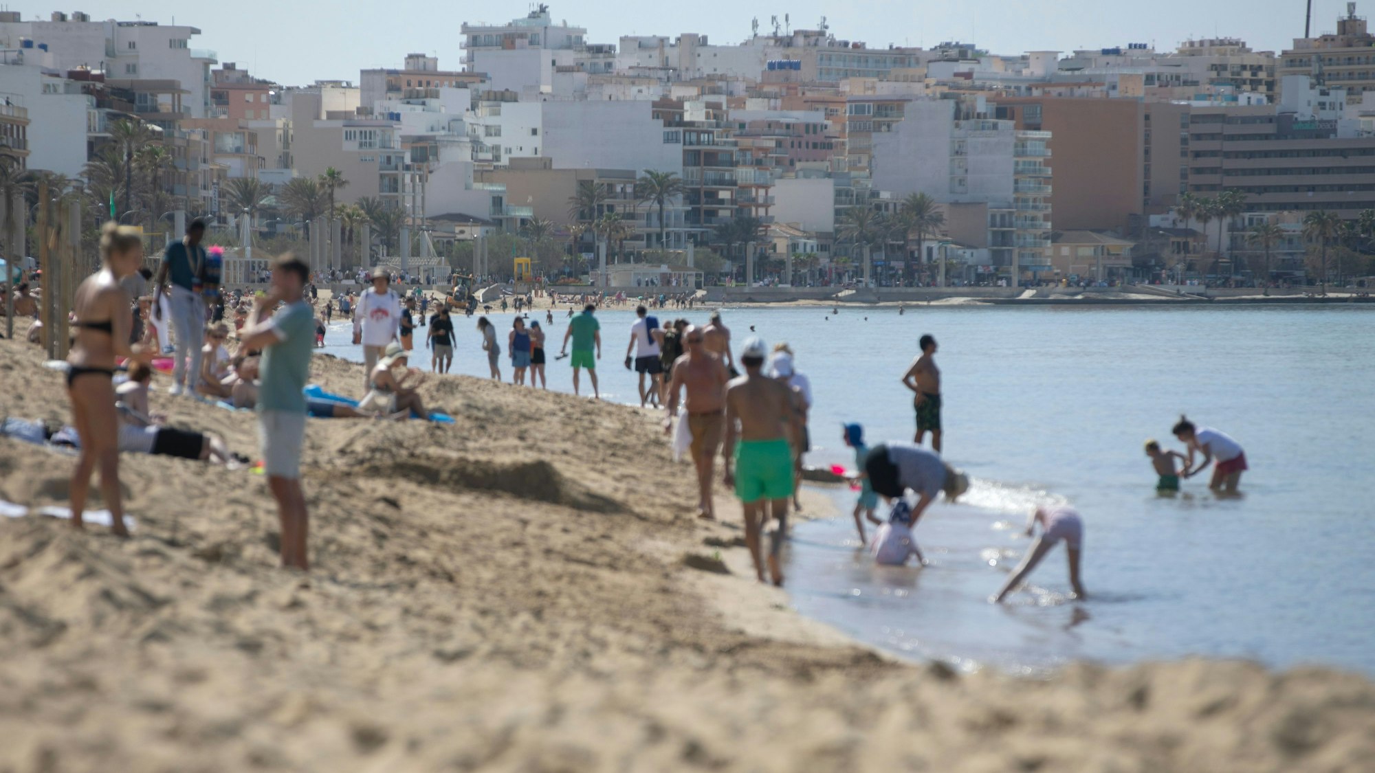 Menschen spazieren am Strand von Arenal auf Mallorca.