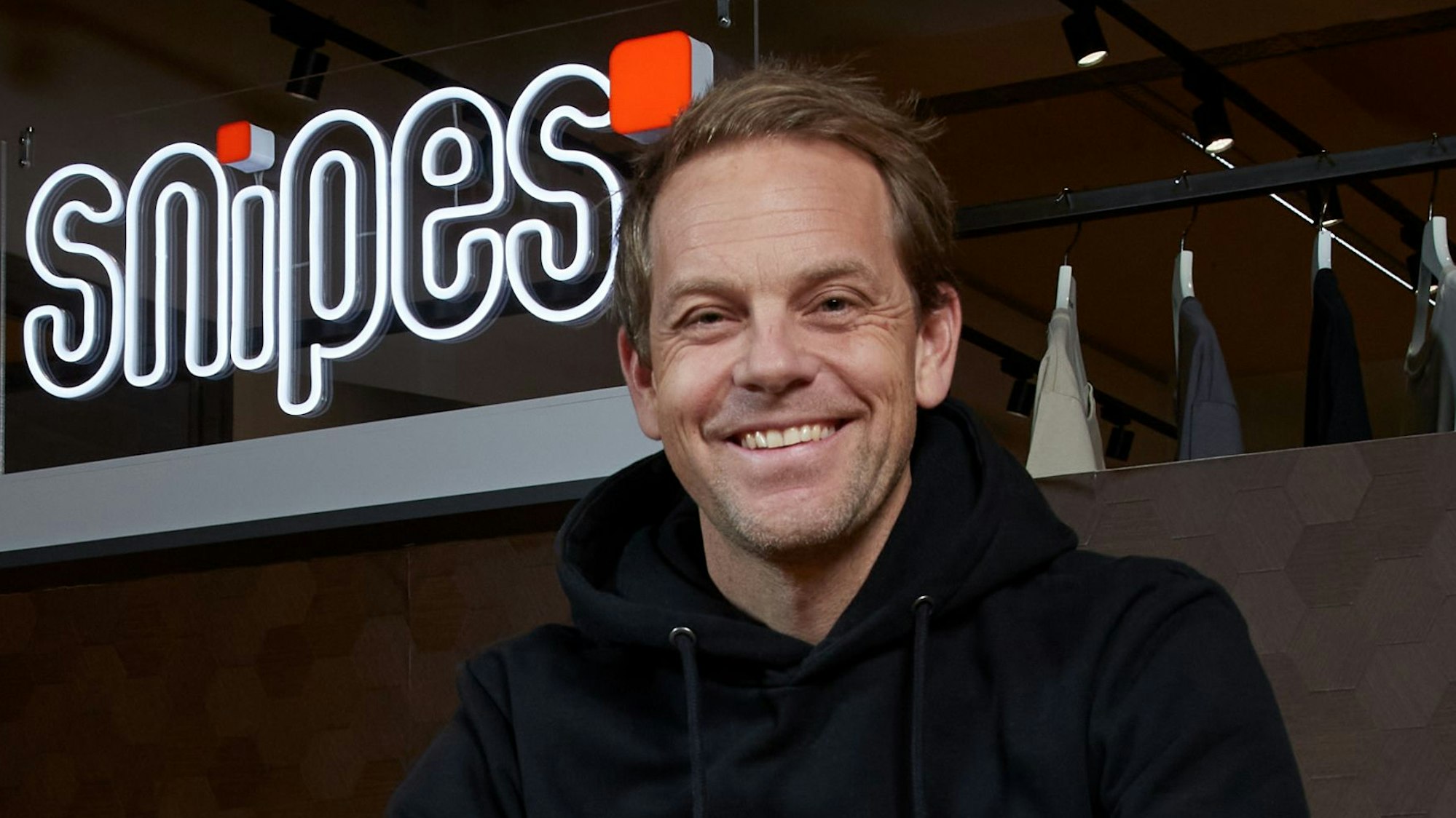 Dennis Schröder sitzt vor einem großen Snipes-Logo.