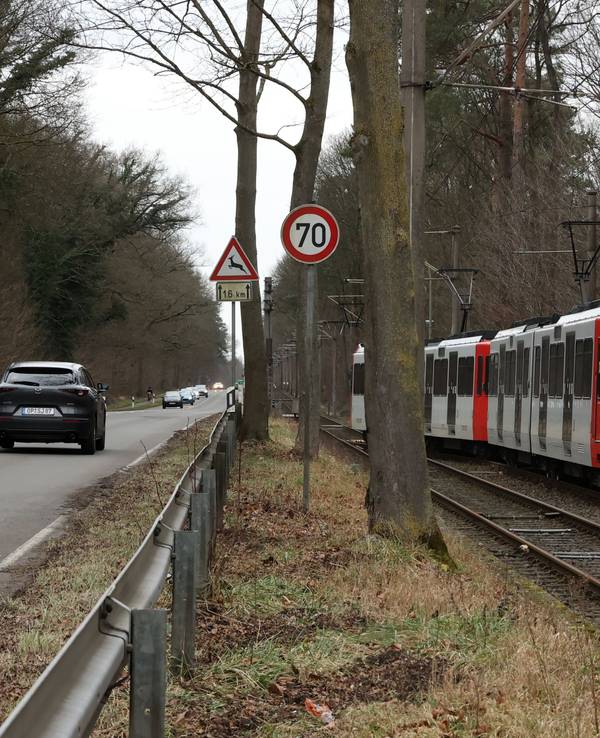 Eine KVB-Bahn der Linie 4 fährt neben Autos an einer Hauptstraße.