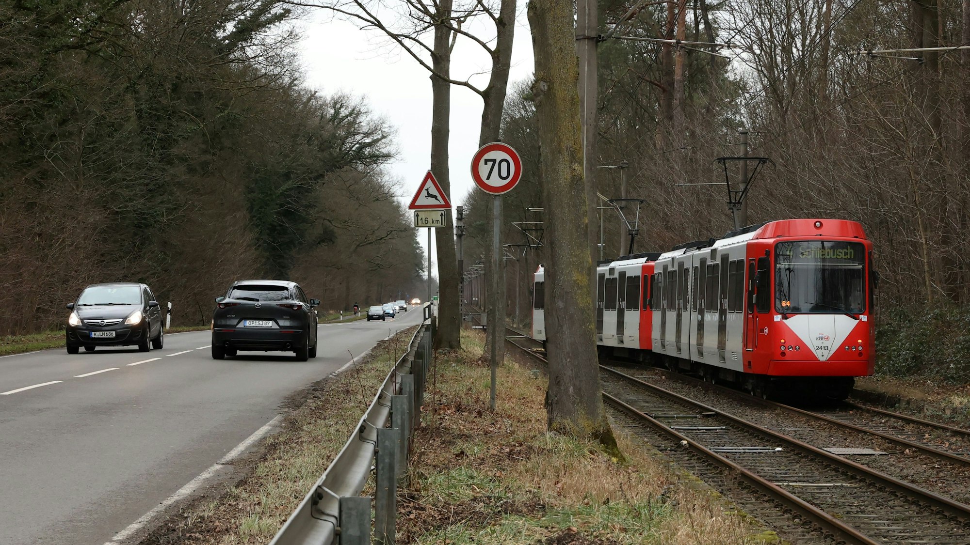 Eine KVB-Bahn der Linie 4 fährt neben Autos an einer Hauptstraße.