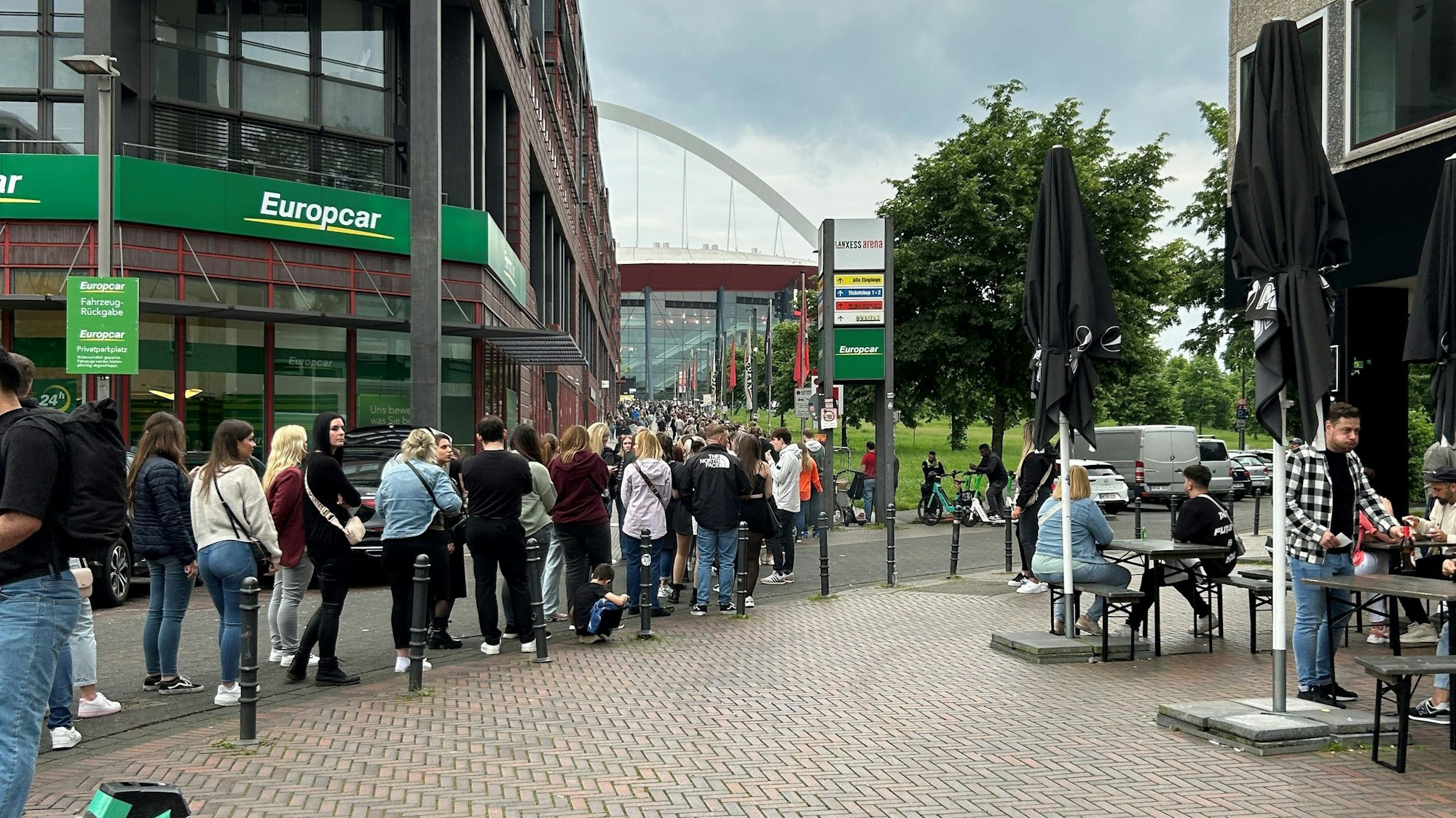 Menschen stehen vor der Lanxess-Arena an.