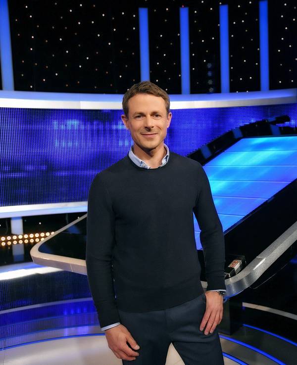Moderator Alexander Bommes steht in der Studiokulisse von „Gefragt - Gejagt“.
