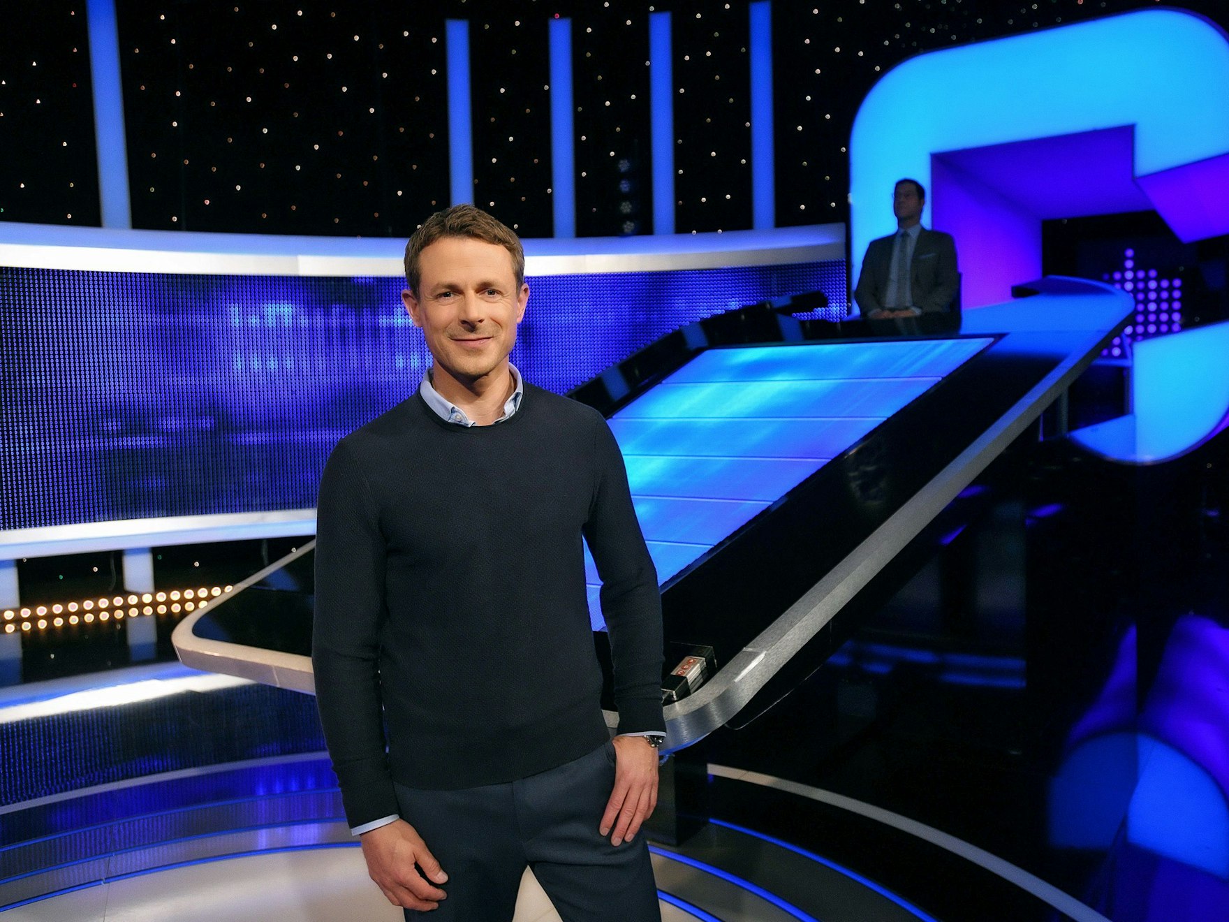 Moderator Alexander Bommes steht in der Studiokulisse von „Gefragt - Gejagt“.