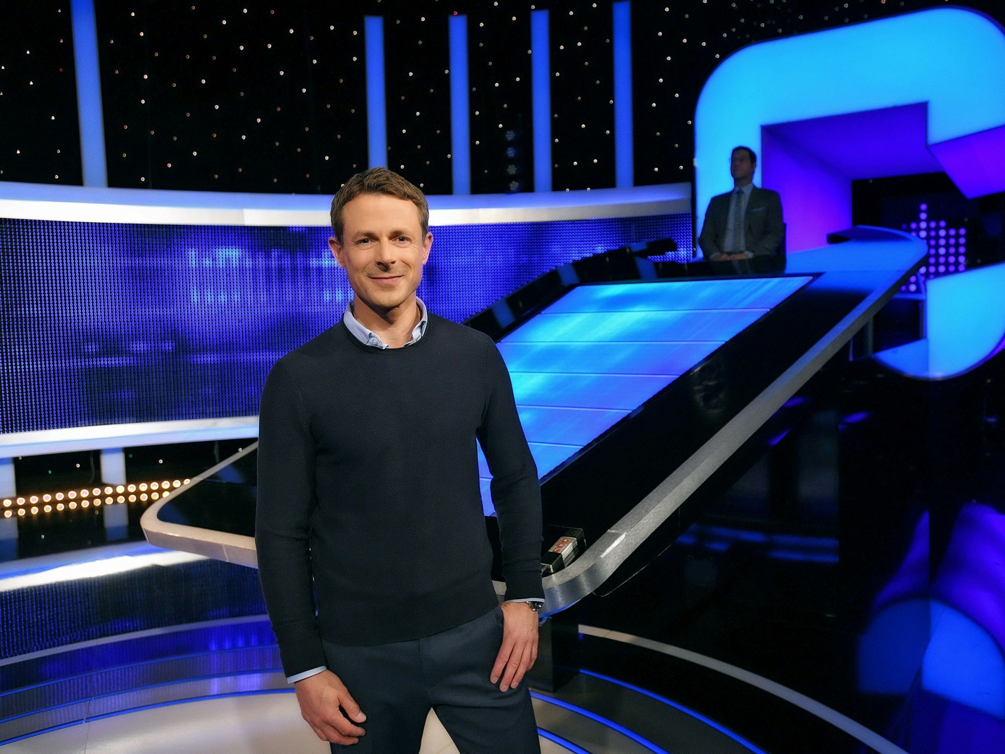 Moderator Alexander Bommes steht in der Studiokulisse von „Gefragt - Gejagt“.