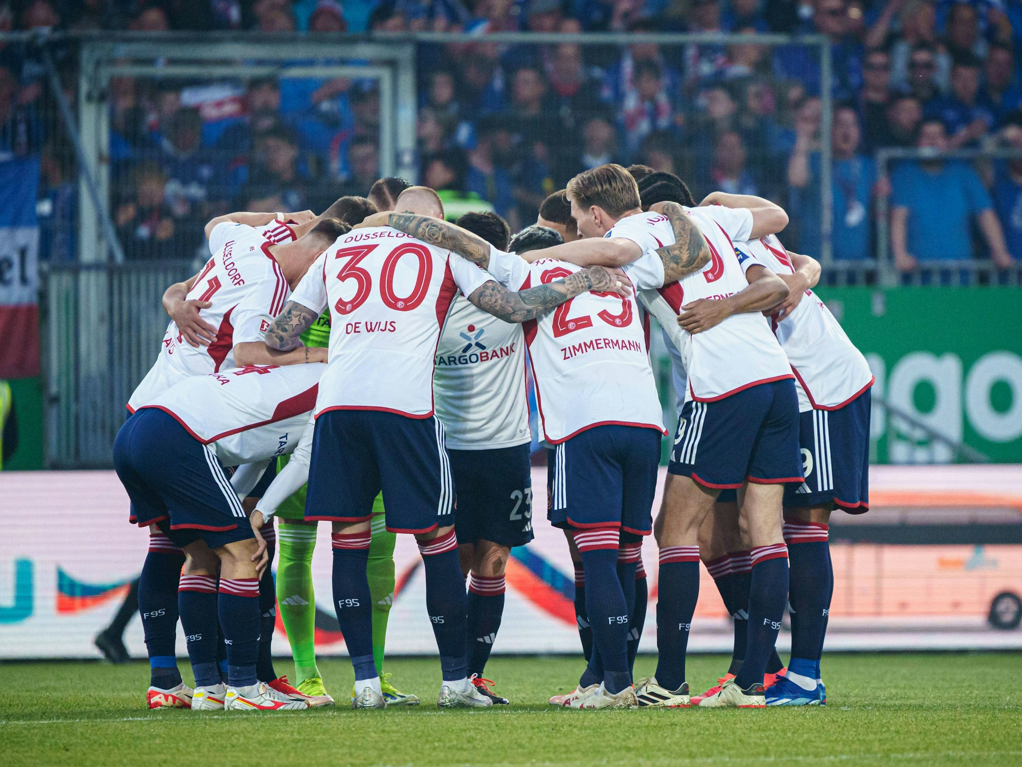 Die Mannschaft von Fortuna Düsseldorf liegt sich für eine Besprechung in den Armen.
