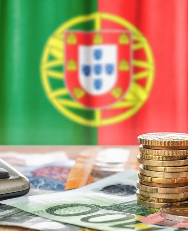 Euro banknotes and coins in front of the national flag of Portugal