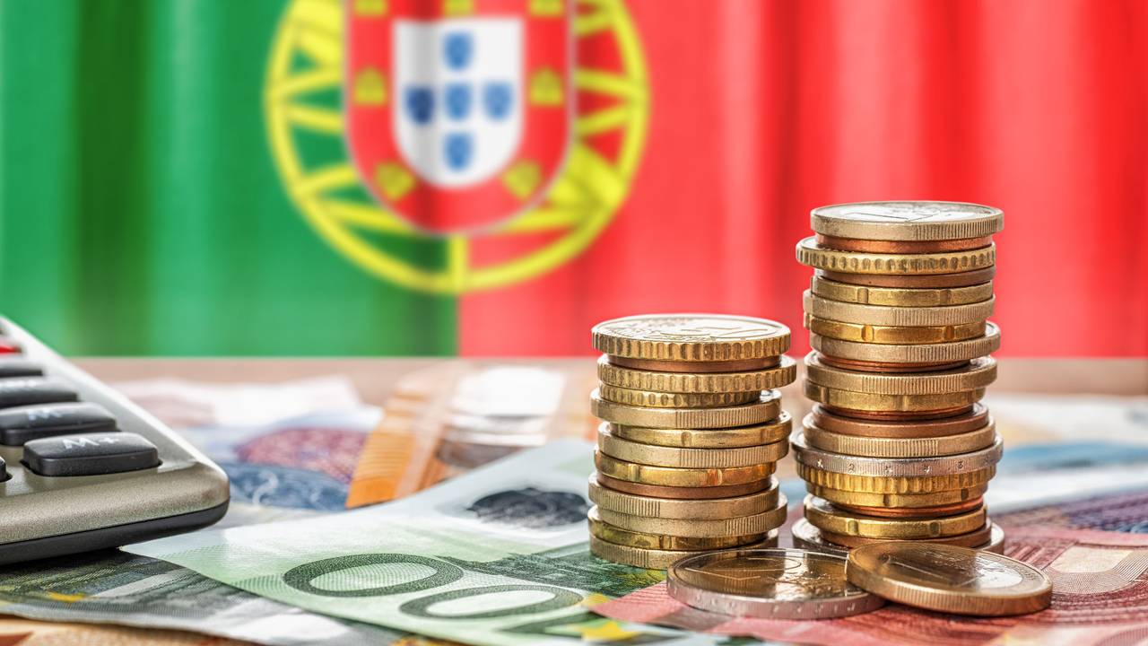 Euro banknotes and coins in front of the national flag of Portugal