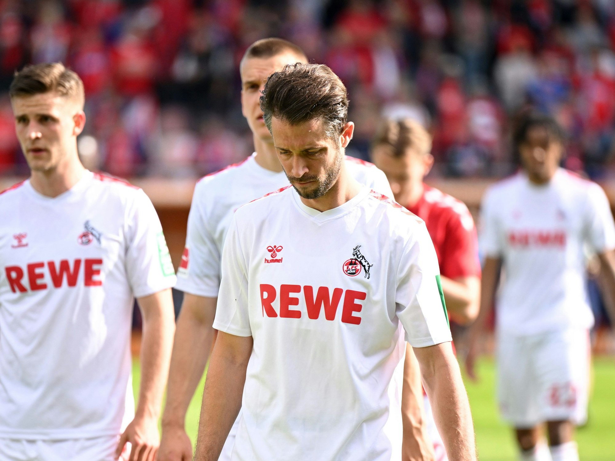Die Kölner Spieler um Mark Uth gehen nach der Niederlage vom Rasen.