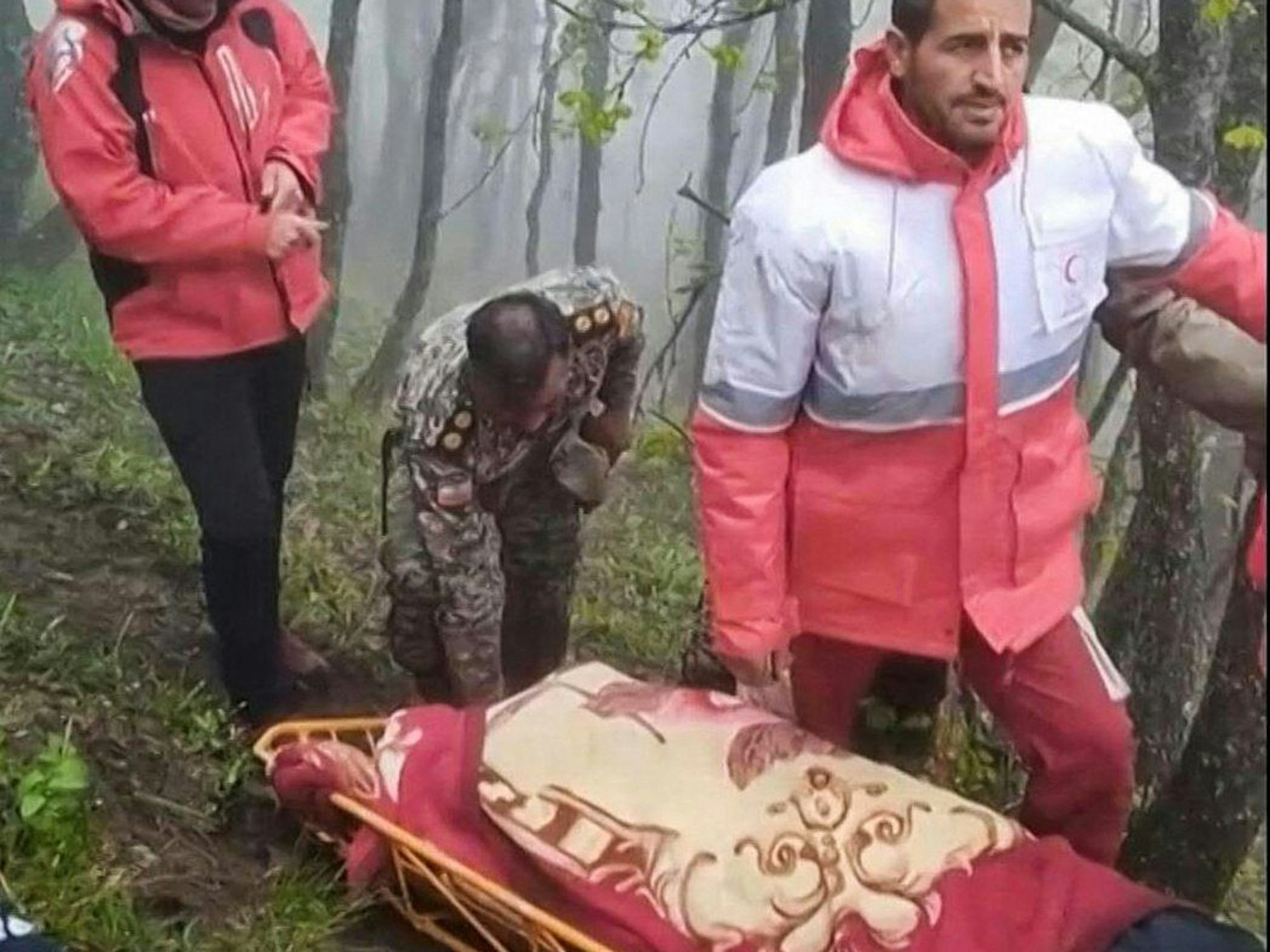 Diese Aufnahme aus einem vom iranischen Roten Halbmond am 20. Mai 2024 veröffentlichten Handout-Video zeigt, wie Rettungskräfte die Leichen des abgestürzten Hubschraubers von Präsident Ebrahim Raisi in einer nebelverhangenen Bergregion im Nordwesten Irans bergen.