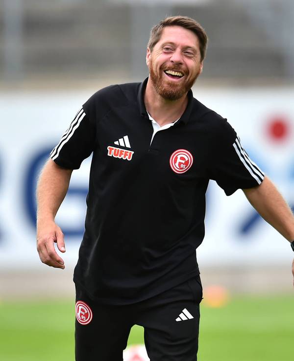 Fortuna Düsseldorfs Co-Trainer Andreas Lambertz steht vor dem Spiel gegen Paderborns U21 lachend auf dem Platz.