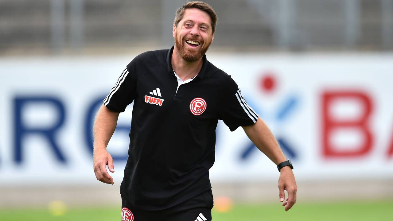 Fortuna Düsseldorfs Co-Trainer Andreas Lambertz steht vor dem Spiel gegen Paderborns U21 lachend auf dem Platz.