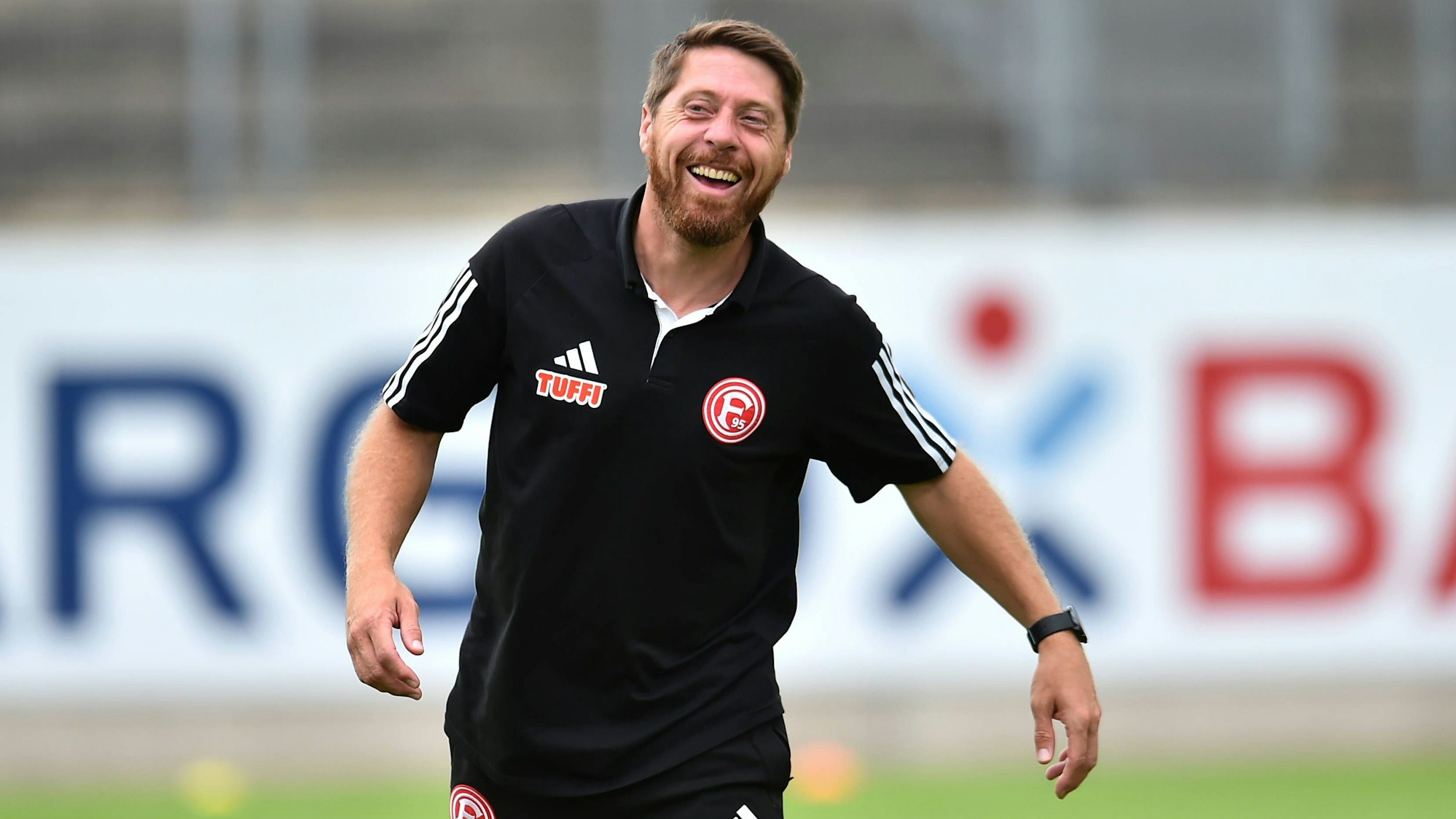 Fortuna Düsseldorfs Co-Trainer Andreas Lambertz steht vor dem Spiel gegen Paderborns U21 lachend auf dem Platz.