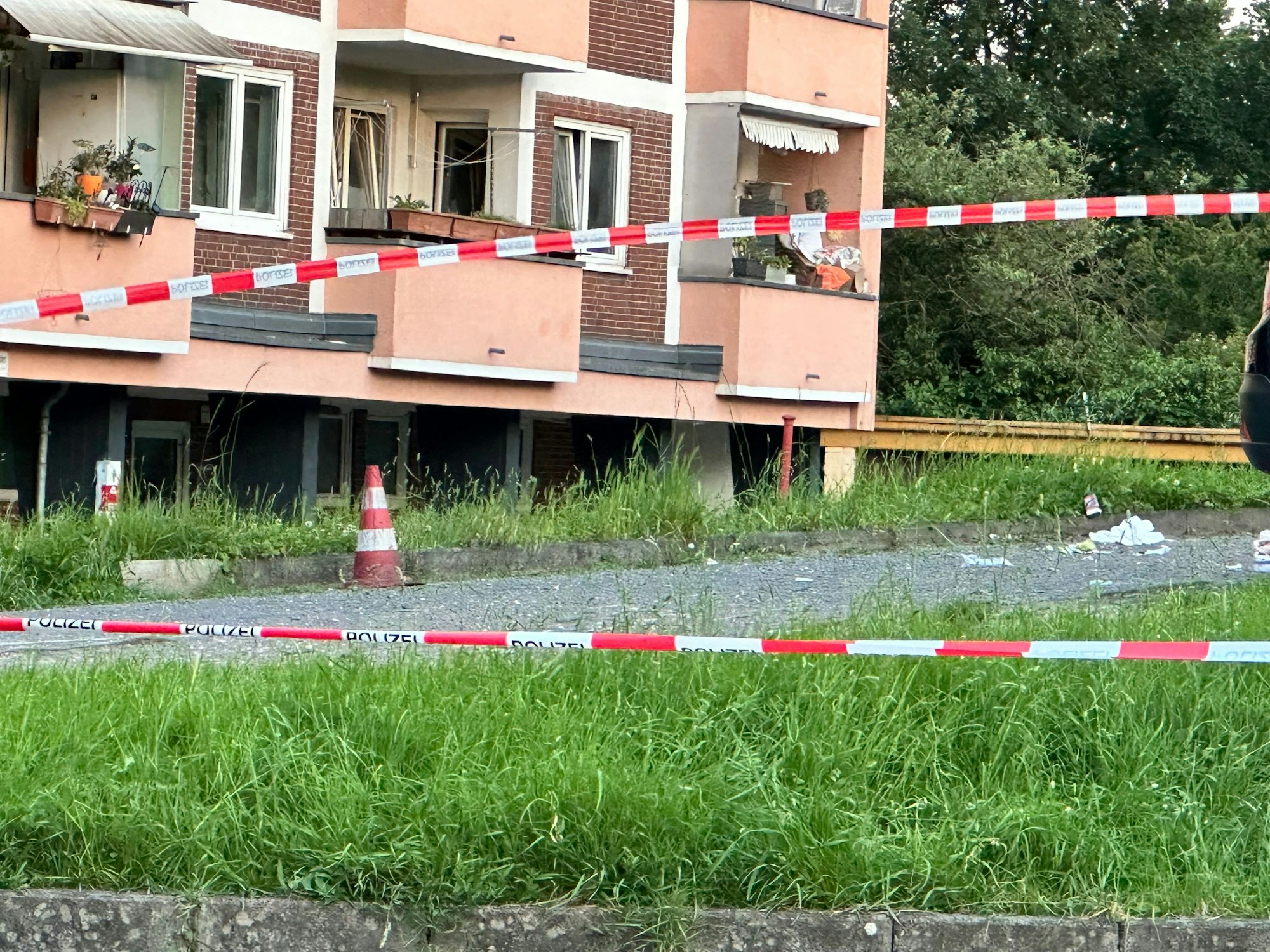 Ein Rasenbereich vor einem Mehrfamilienhaus wurde mit Flatterband der Polizei abgesperrt.