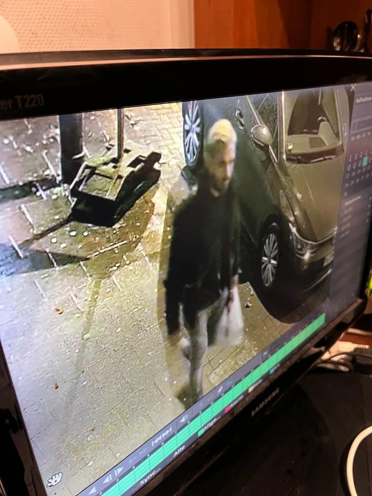 Ein Mann geht an einem geparkten Auto entlang.