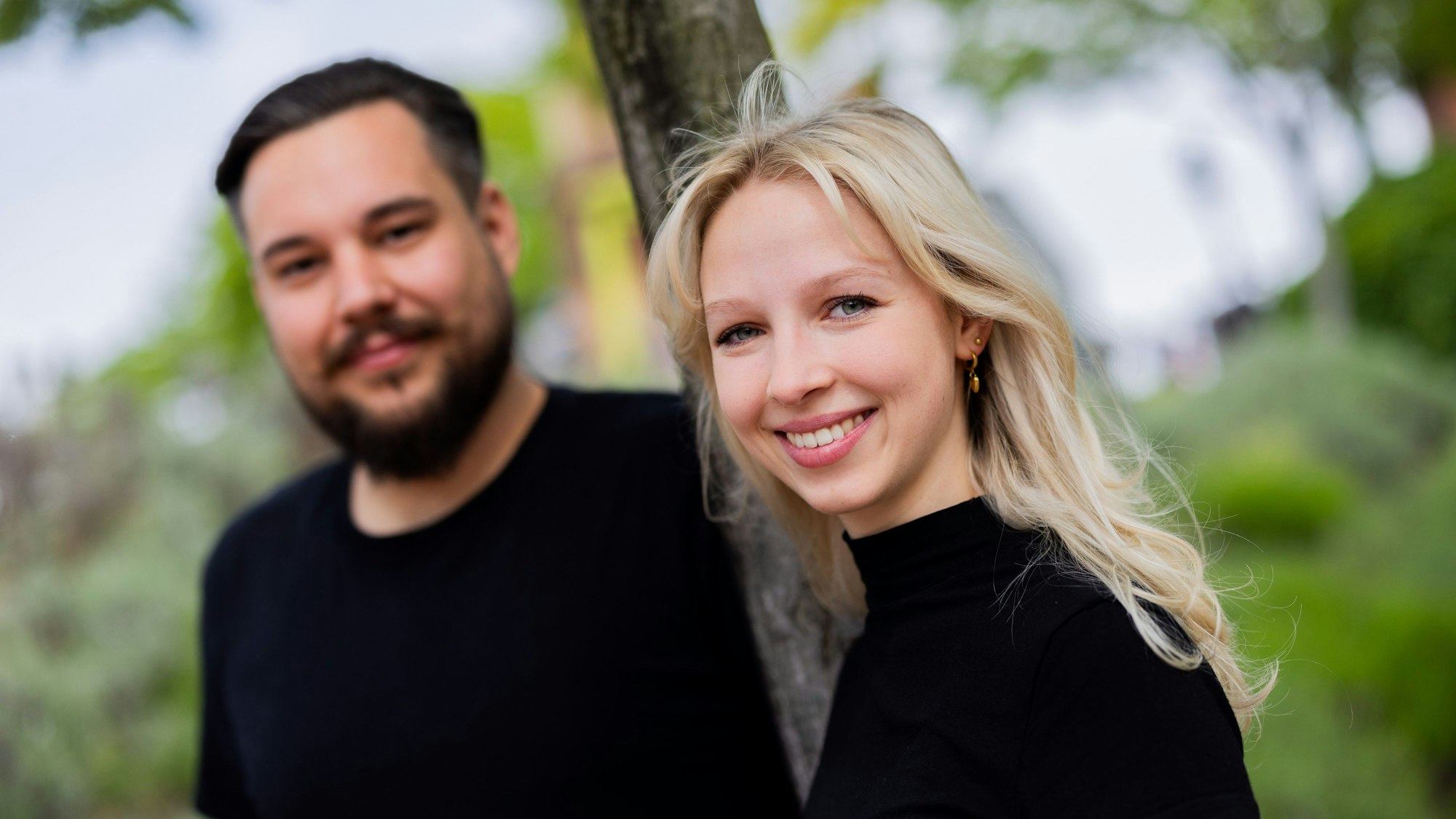 Tina Kunath und Jan Wolfenstädter stehen gemeinsam am Rheinufer in Köln und schauen in die Kamera.