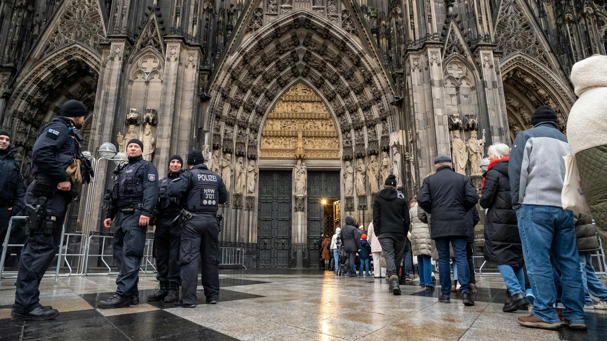 Polizei und Besucher stehen vor dem Hauptportal des Kölner Doms.