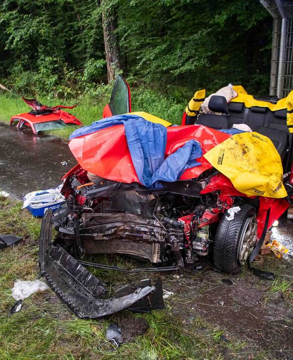 Ein Auto steht auf einem Gehweg, das abgetrennte Dach liegt ein paar Meter entfernt auf dem Boden. Die Stoßstange des Wagens ist abgerissen.