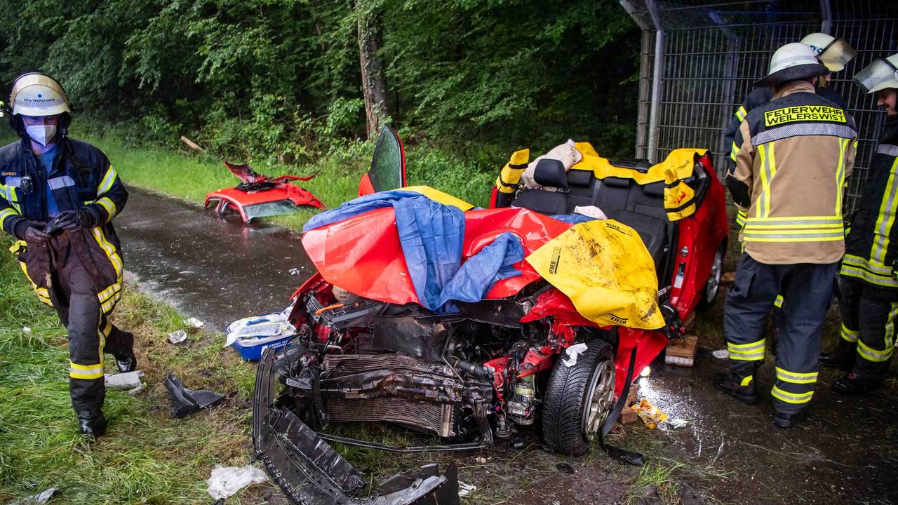 Ein Auto steht auf einem Gehweg, das abgetrennte Dach liegt ein paar Meter entfernt auf dem Boden. Die Stoßstange des Wagens ist abgerissen.