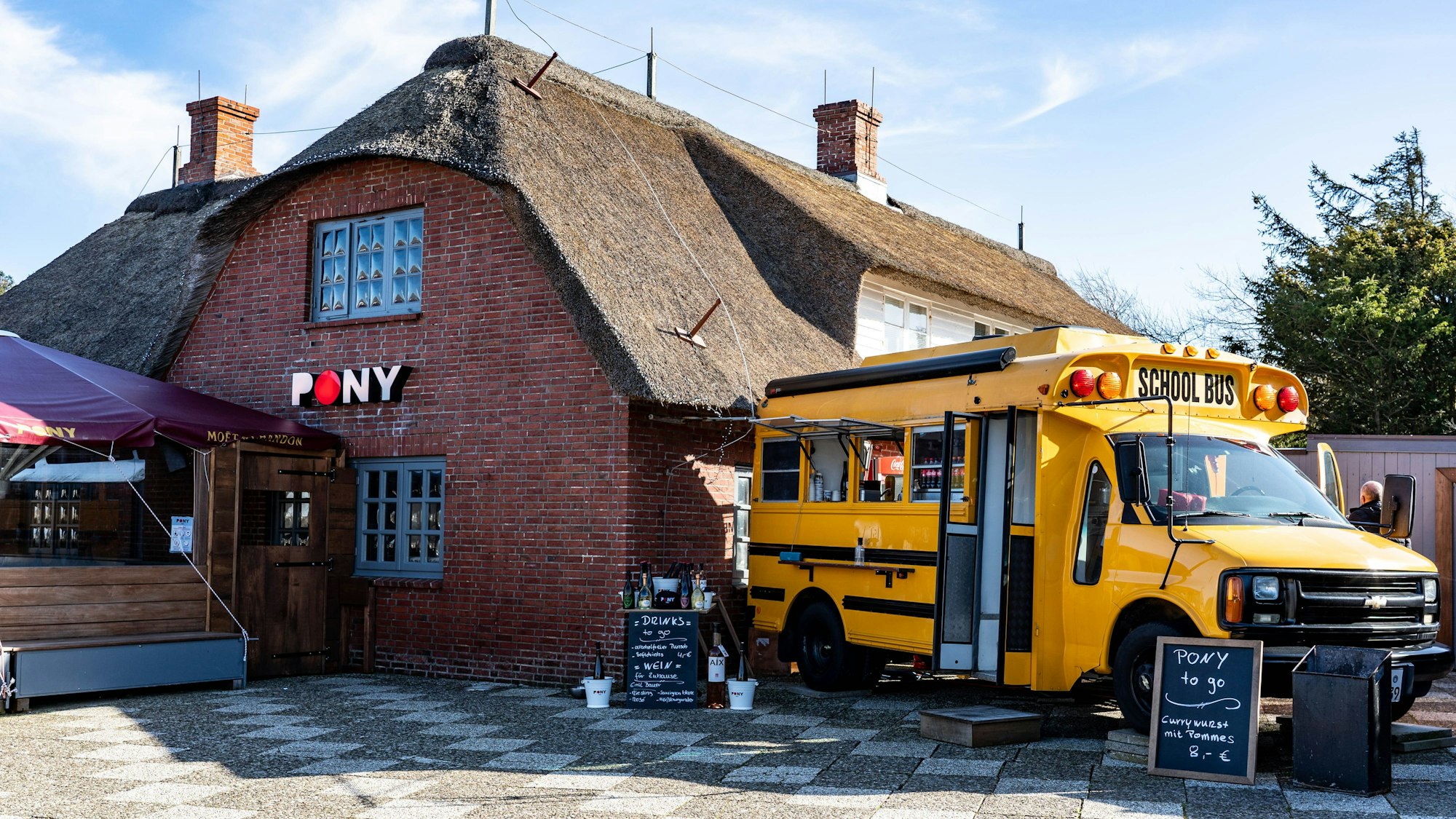 Ein alter amerikanischer Schulbus steht als Ausschank neben der Gaststätte „Pony“ in der Straße Strönwai im Zentrum von Kampen. (Illustration zu "Empörung nach Video mit rassistischem Gegröle - Sylter Lokal betroffen") +++ dpa-Bildfunk +++