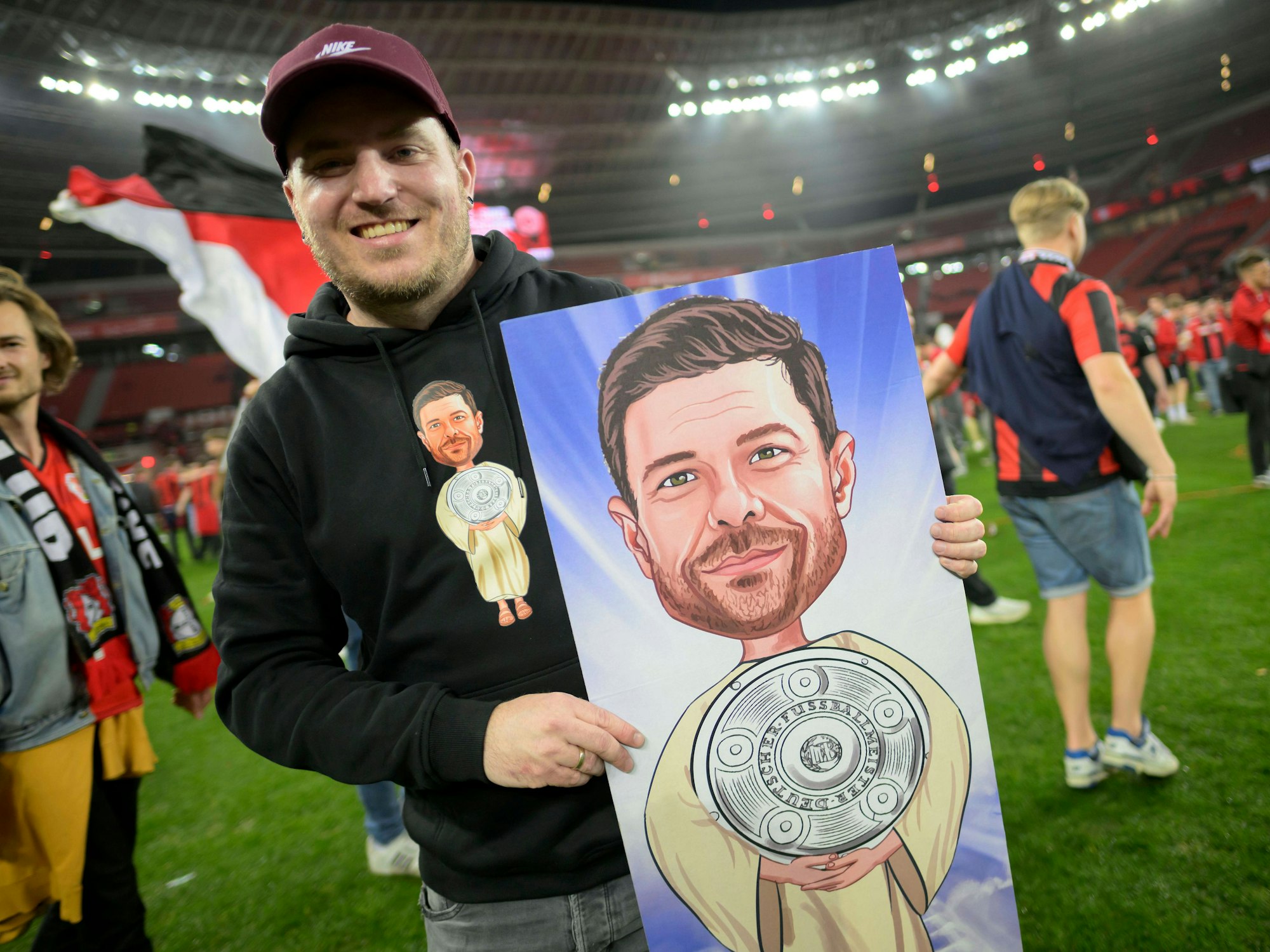 Bayer-Fan Maciek Gawlik hält auf dem Spielfeld seine Abbildung von Xabi Alonso als Messias in der Hand.