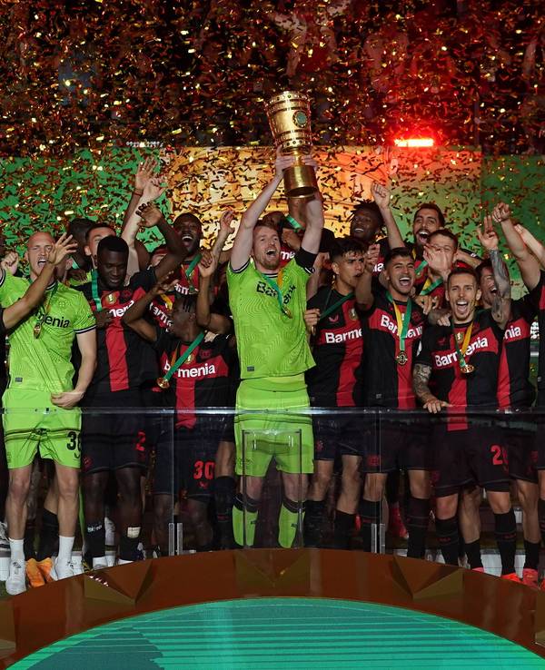 Der Kapitän von Bayer Leverkusen, Lukas Hradecky, hebt umringt von seinen Teamkollegen den DFB-Pokal in die Höhe.