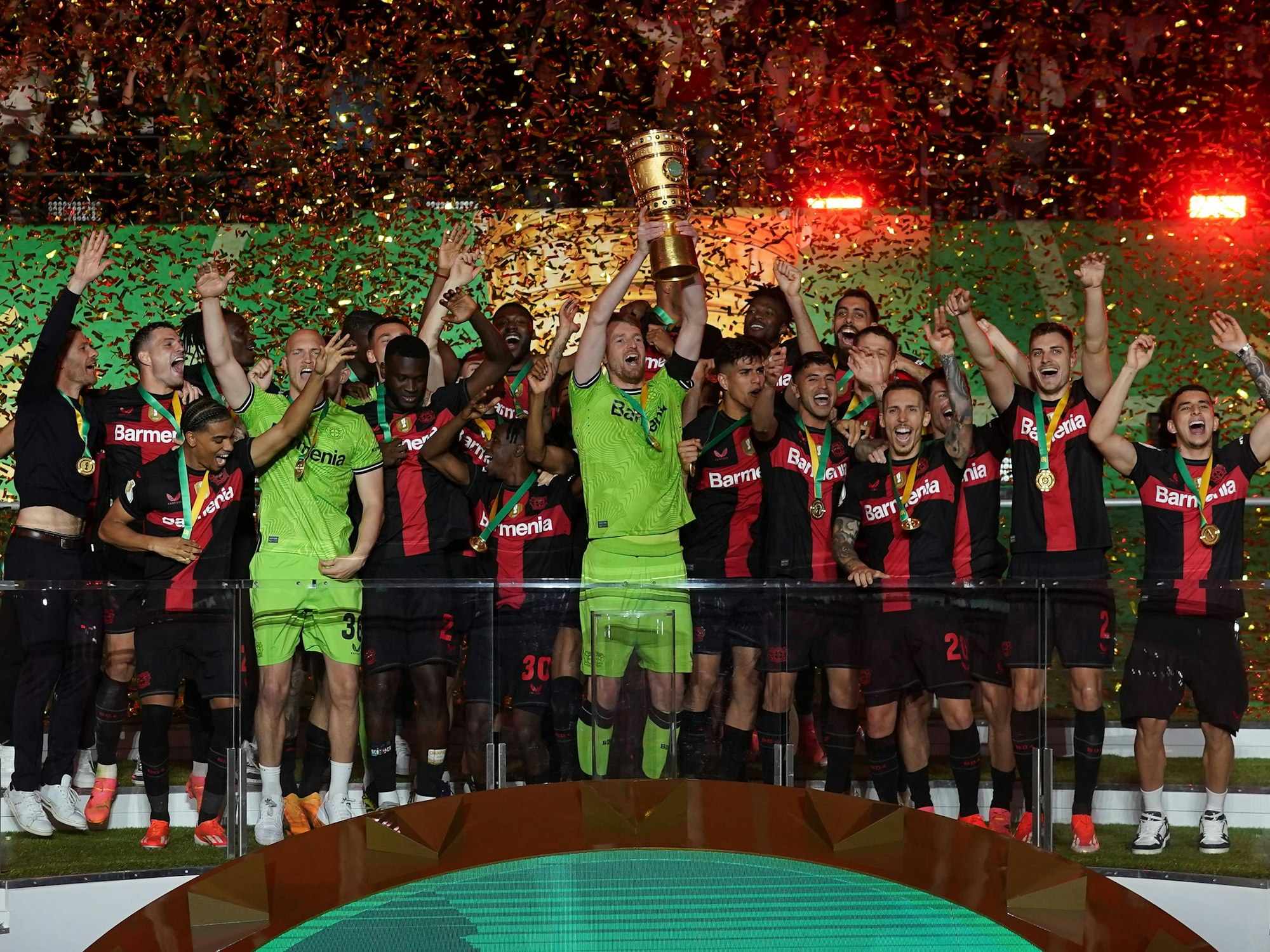 Der Kapitän von Bayer Leverkusen, Lukas Hradecky, hebt umringt von seinen Teamkollegen den DFB-Pokal in die Höhe.