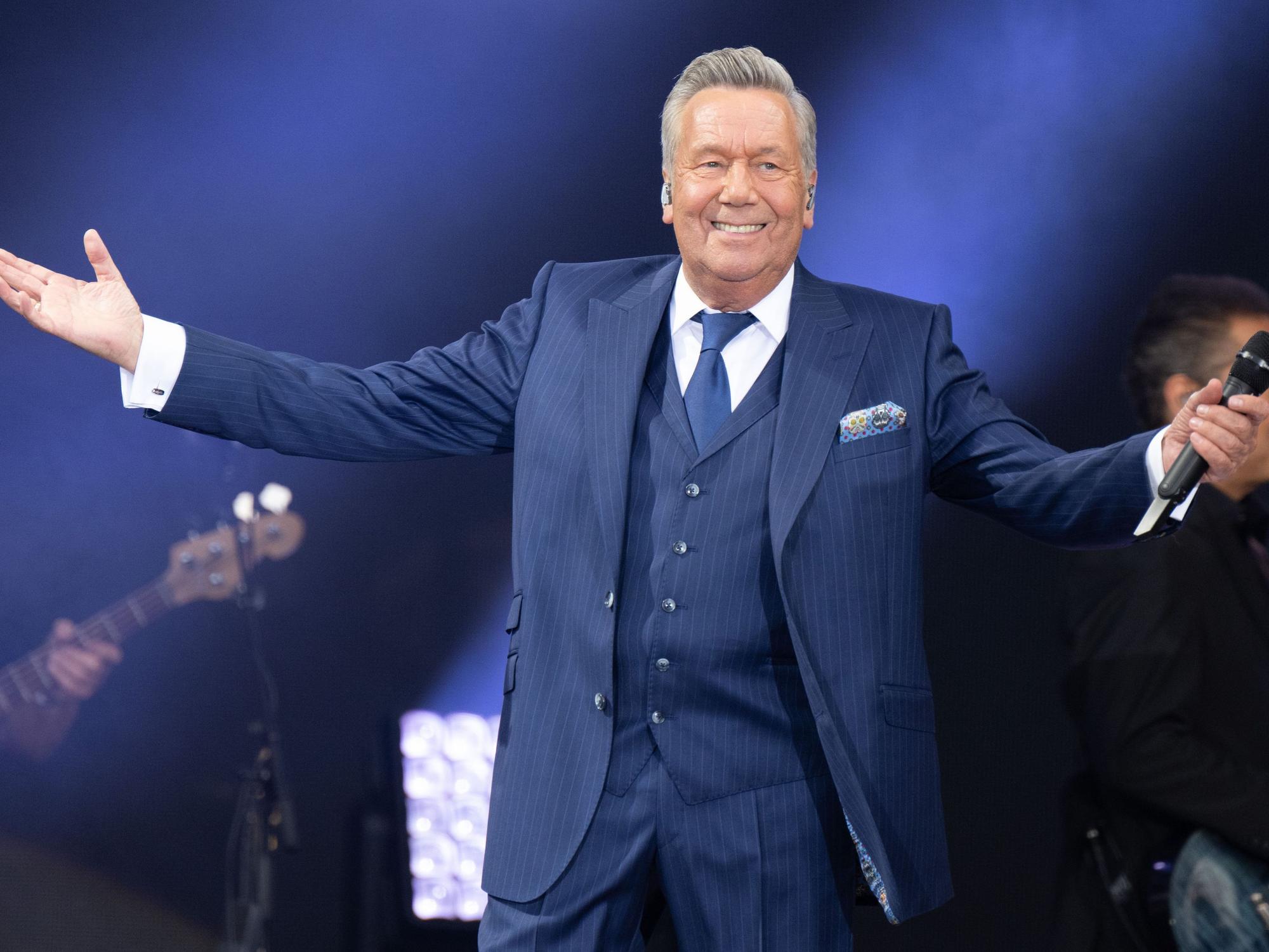 Der deutsche Schlagersänger Roland Kaiser lacht und breitet seine Arme aus bei seinem Konzert im Rahmen der „Kaisermania“ am Elbufer im Jahr 2022.