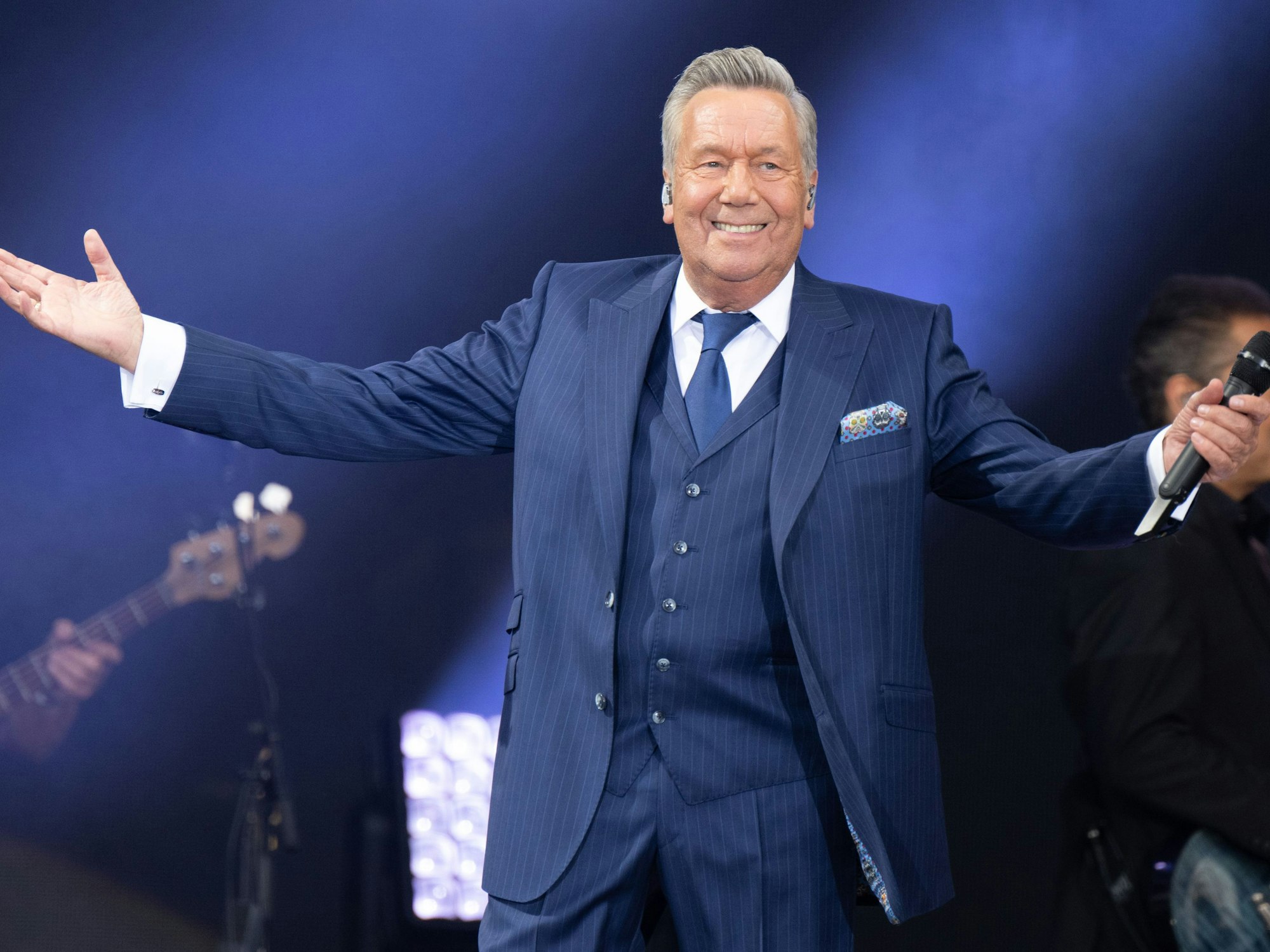 Der deutsche Schlagersänger Roland Kaiser lacht und breitet seine Arme aus bei seinem Konzert im Rahmen der „Kaisermania“ am Elbufer im Jahr 2022.