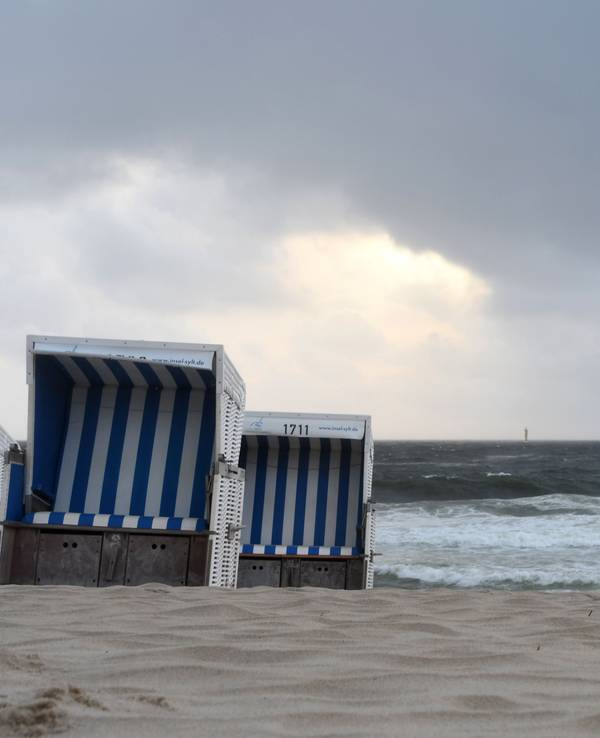 Leere Strandkörbe stehen am Strand.