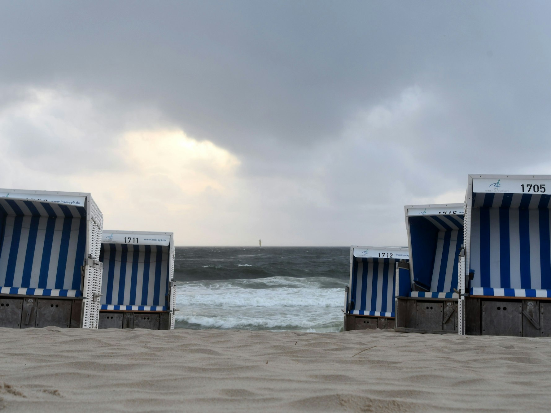 Leere Strandkörbe stehen am Strand.