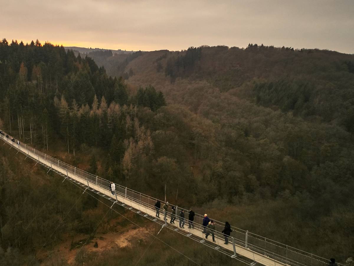 Besucher gehen auf der Hängeseilbrücke Geierlay hoch über einem Mosel-Seitental bei Mörsdorf im Hunsrück