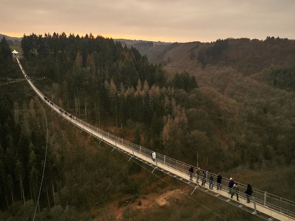 Besucher gehen auf der Hängeseilbrücke Geierlay hoch über einem Mosel-Seitental bei Mörsdorf im Hunsrück